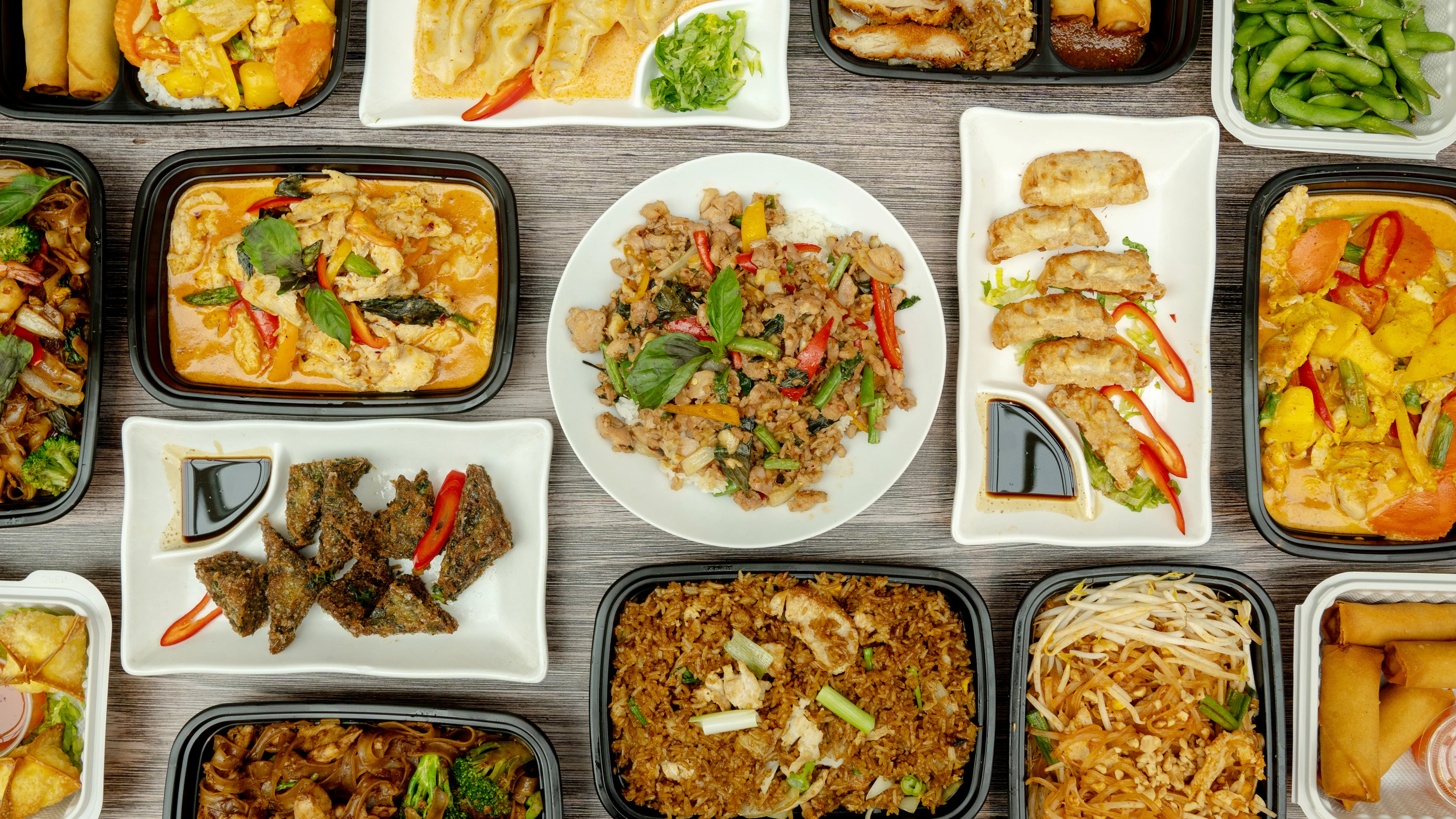 Assorted Thai dishes including pad thai and curry in takeout containers