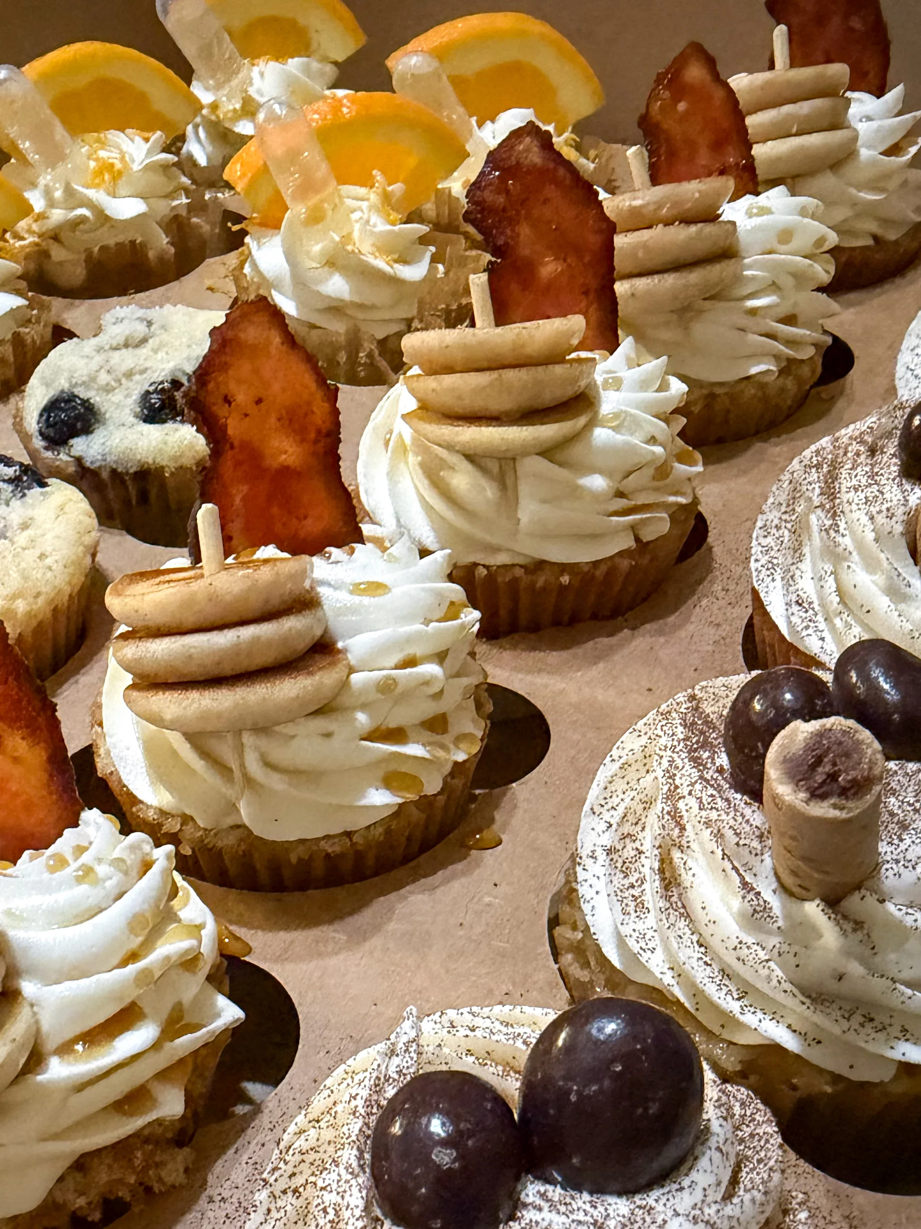 A variety of decorated cupcakes with unique toppings and designs.