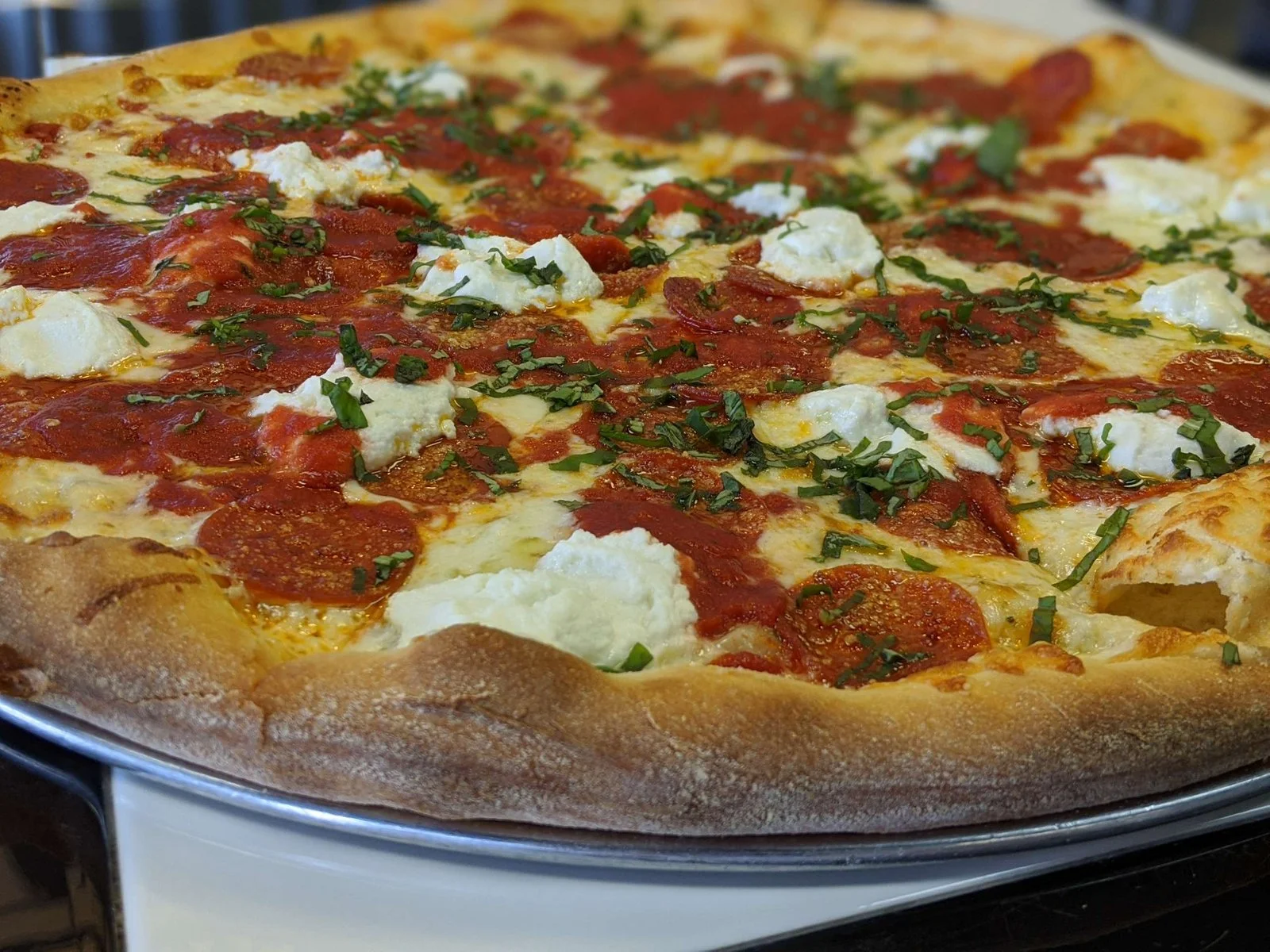A pepperoni pizza with green onions and pockets of mozzarella 