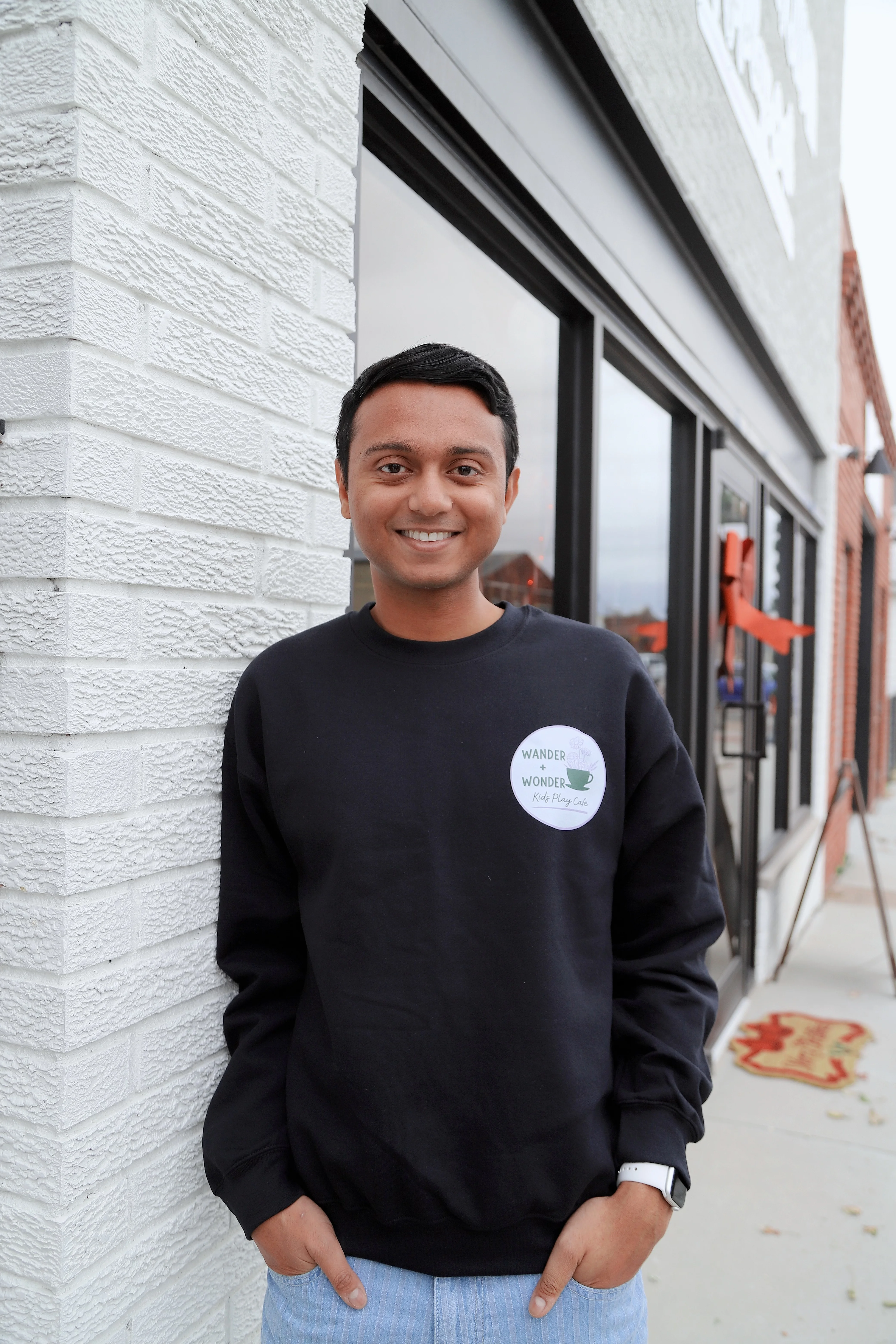 Smiling barista outside a cozy café with a welcoming atmosphere