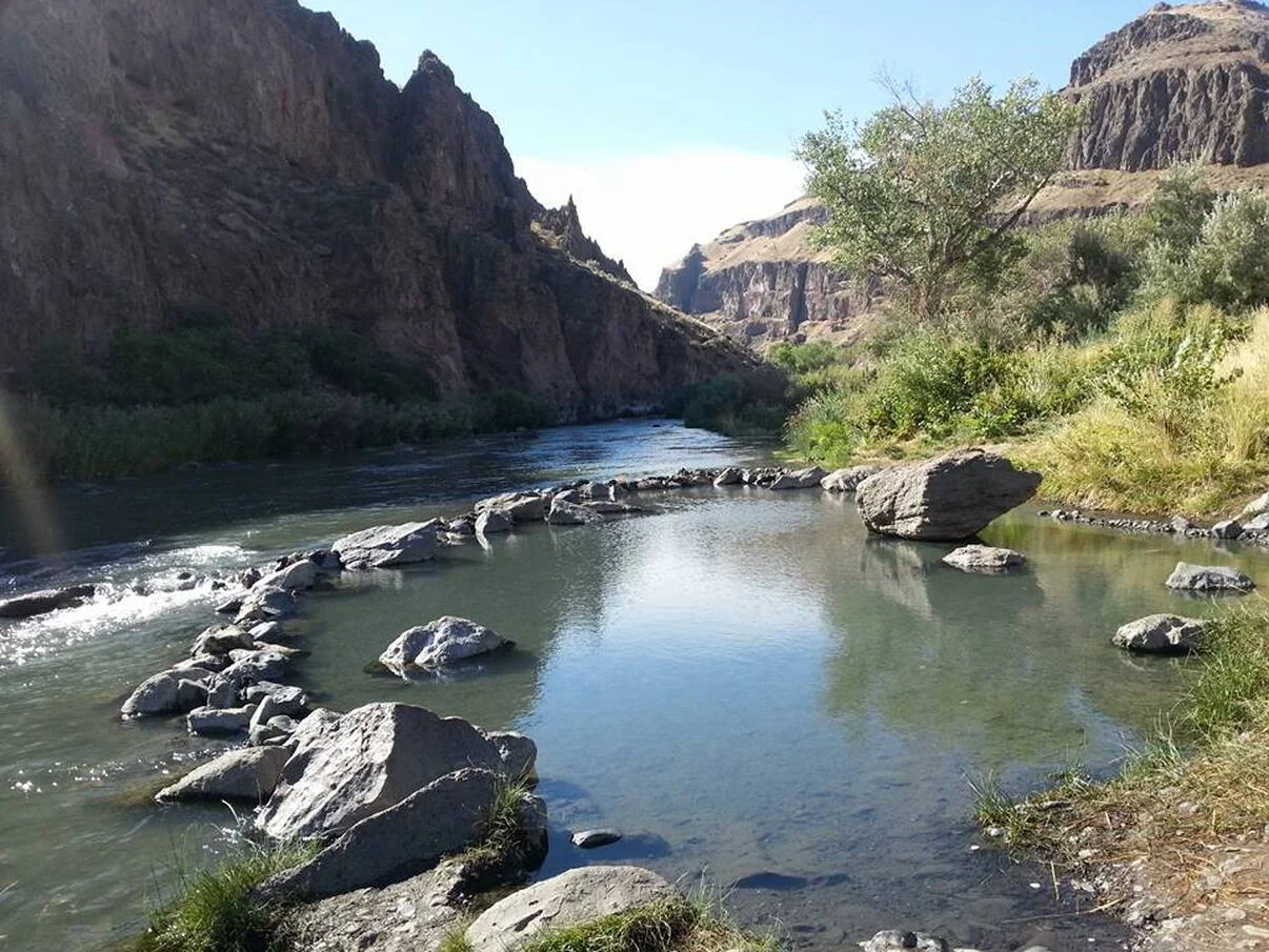Scenic river view surrounded by rocky cliffs and greenery