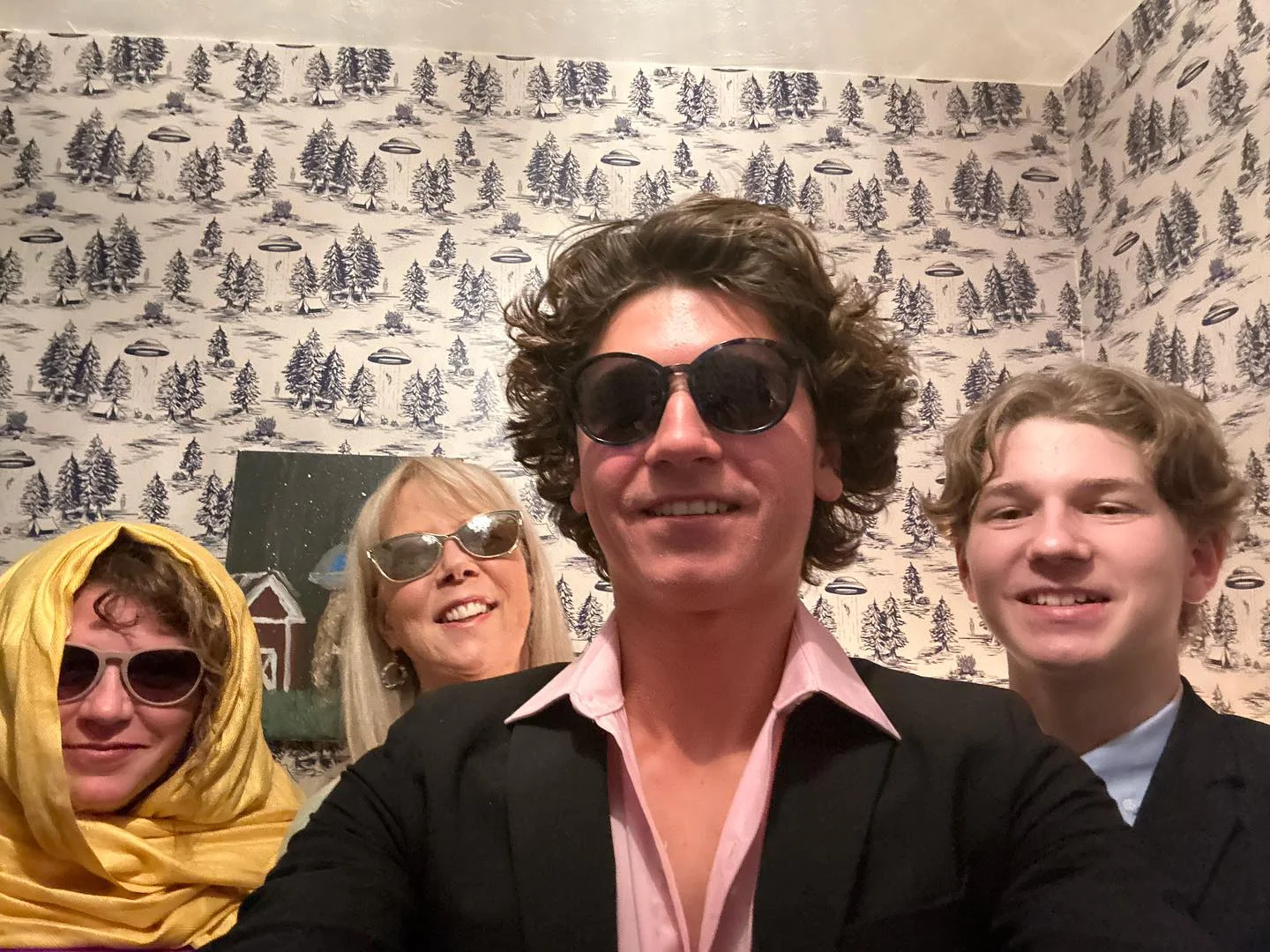 Group selfie with stylish outfits and sunglasses in a cozy setting