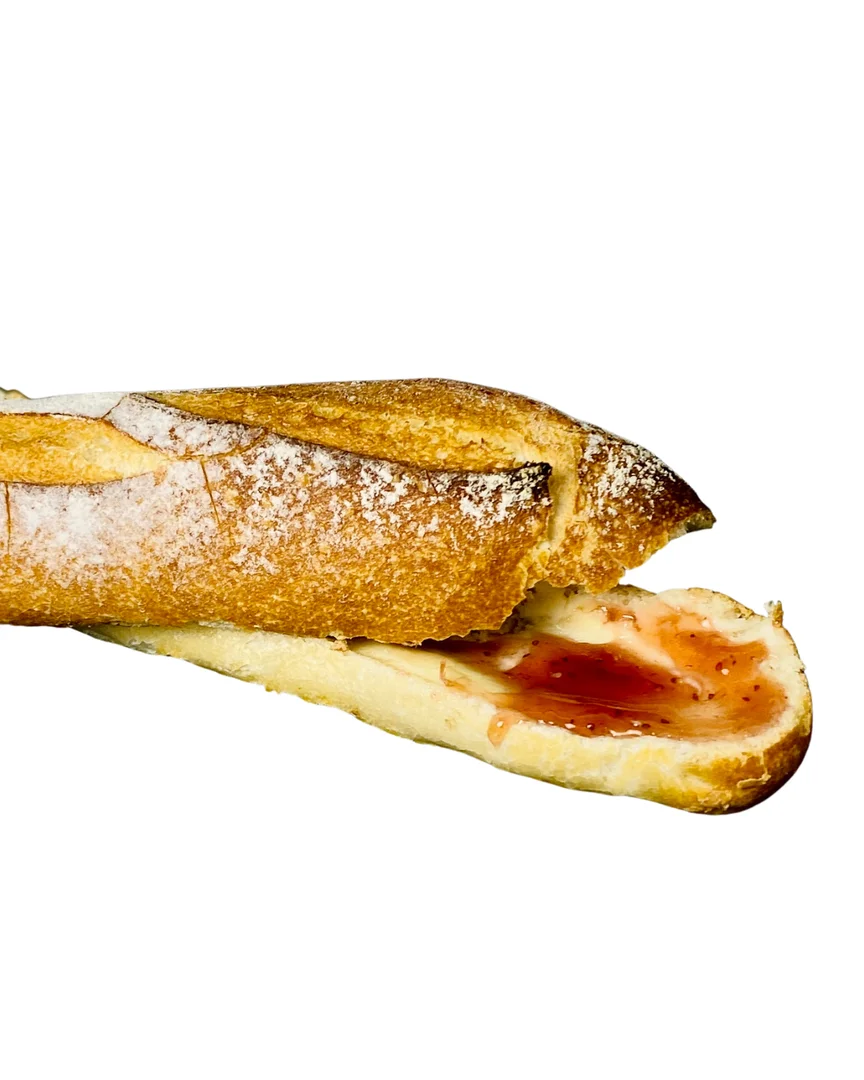 A sliced baguette with a dollop of strawberry jam spread inside.