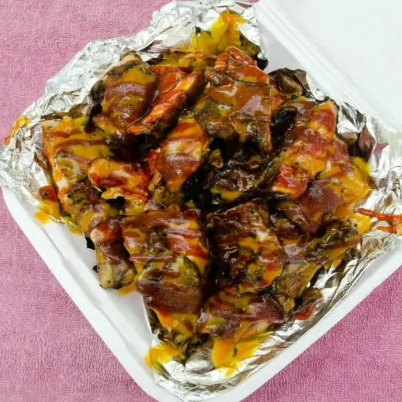A serving of grilled meat with sauces in a takeout container.