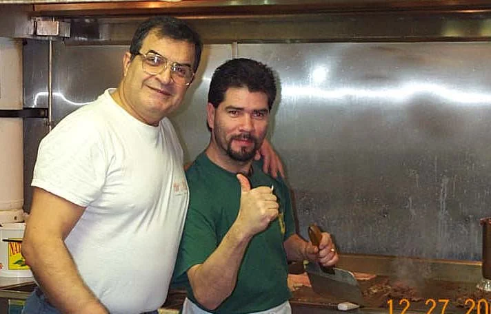 Chefs smiling in a bustling restaurant kitchen