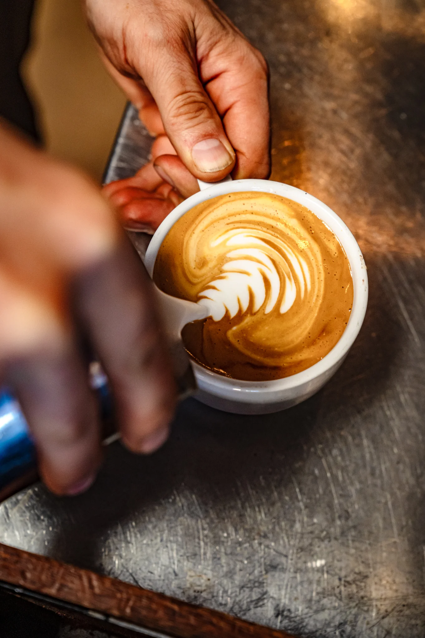 Barista pouring latte art into a cup of coffee