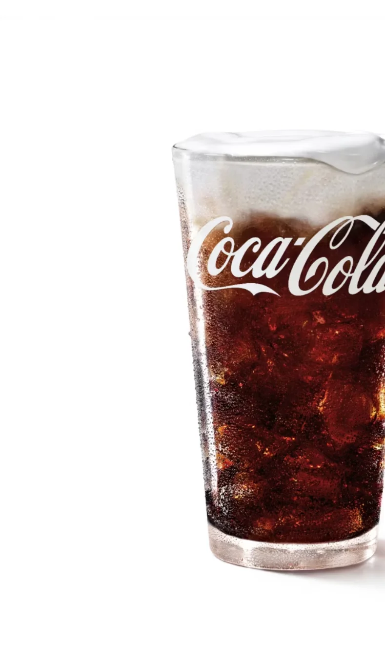 Chilled glass of Coca-Cola with ice and foam