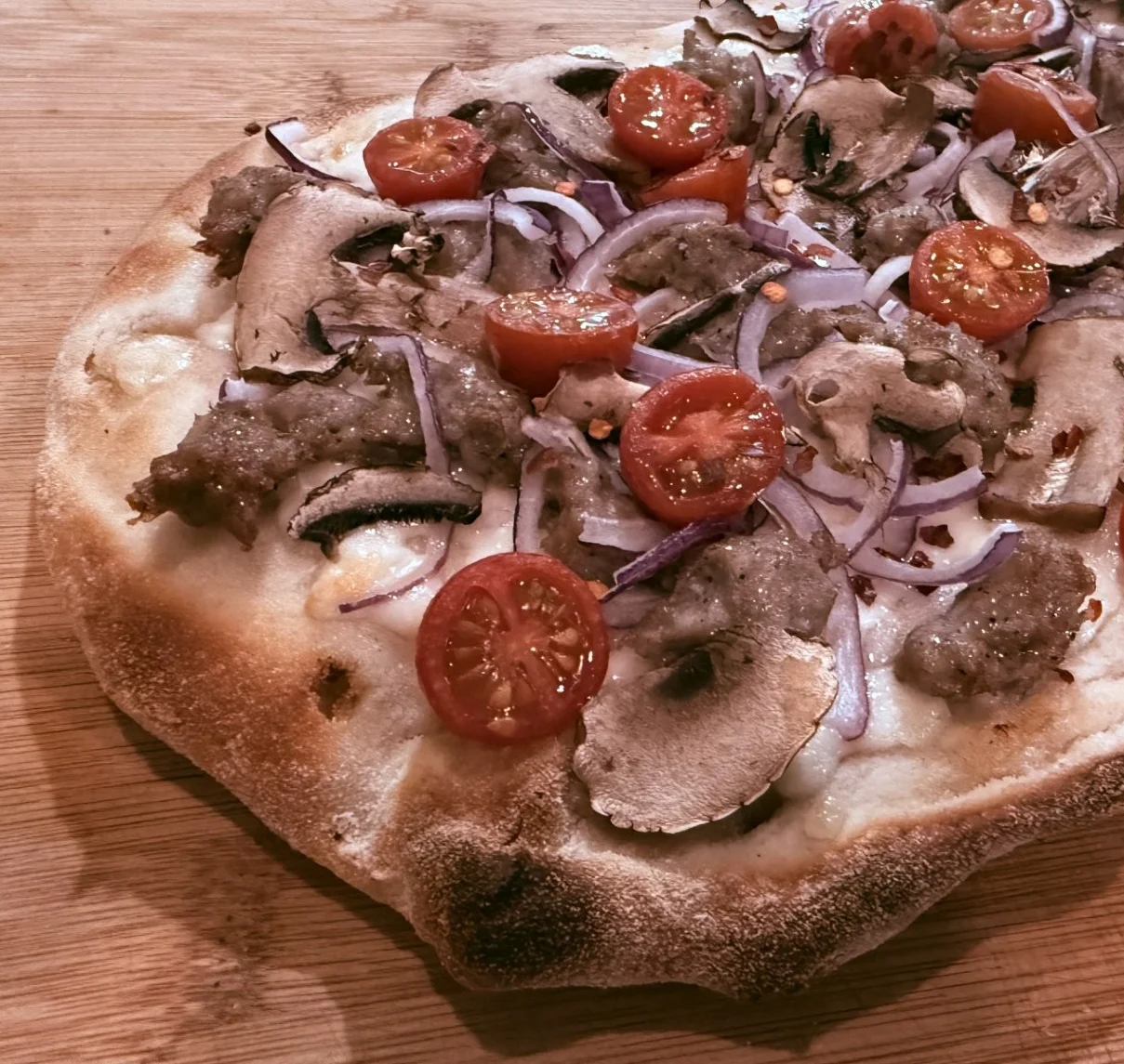 Iinsa Romana with fresh mozzarella, Italian sausage, cherry tomatoes, red onion and mushrooms at Daje Pinsa Roman Pizza, Orlando.