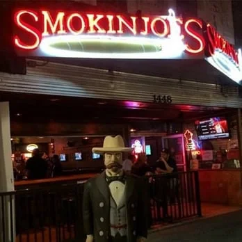 Bartenders posing at a stylish bar with whiskey bottles in the background