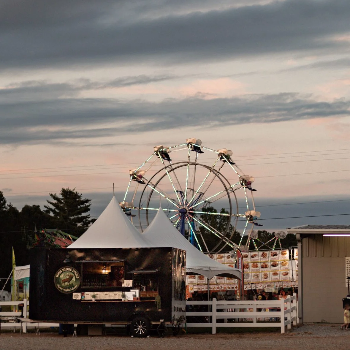 Food truck at a fair with a ferris wheel in the background