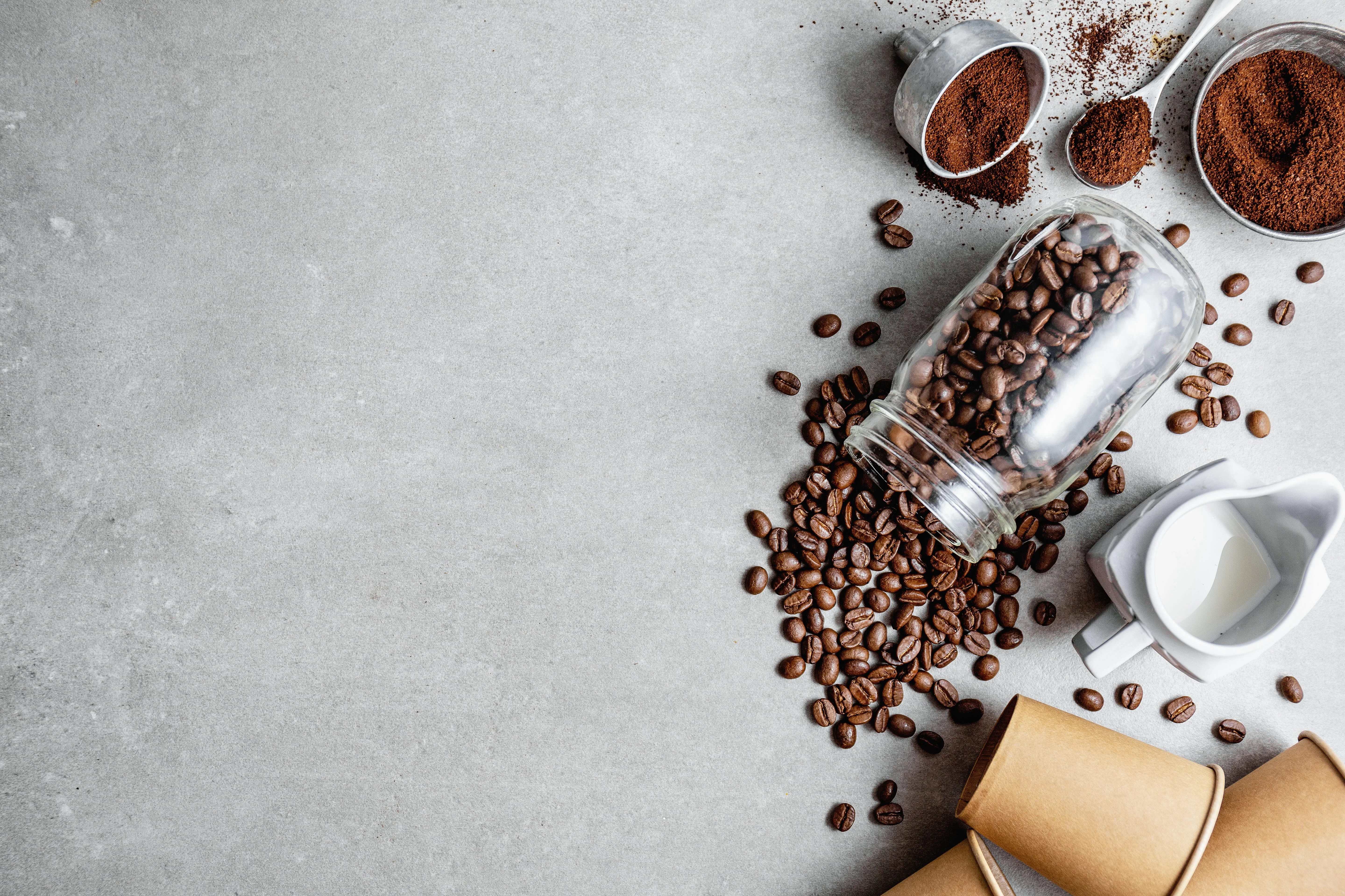 Coffee beans and grounds with a glass jar and cream pitcher