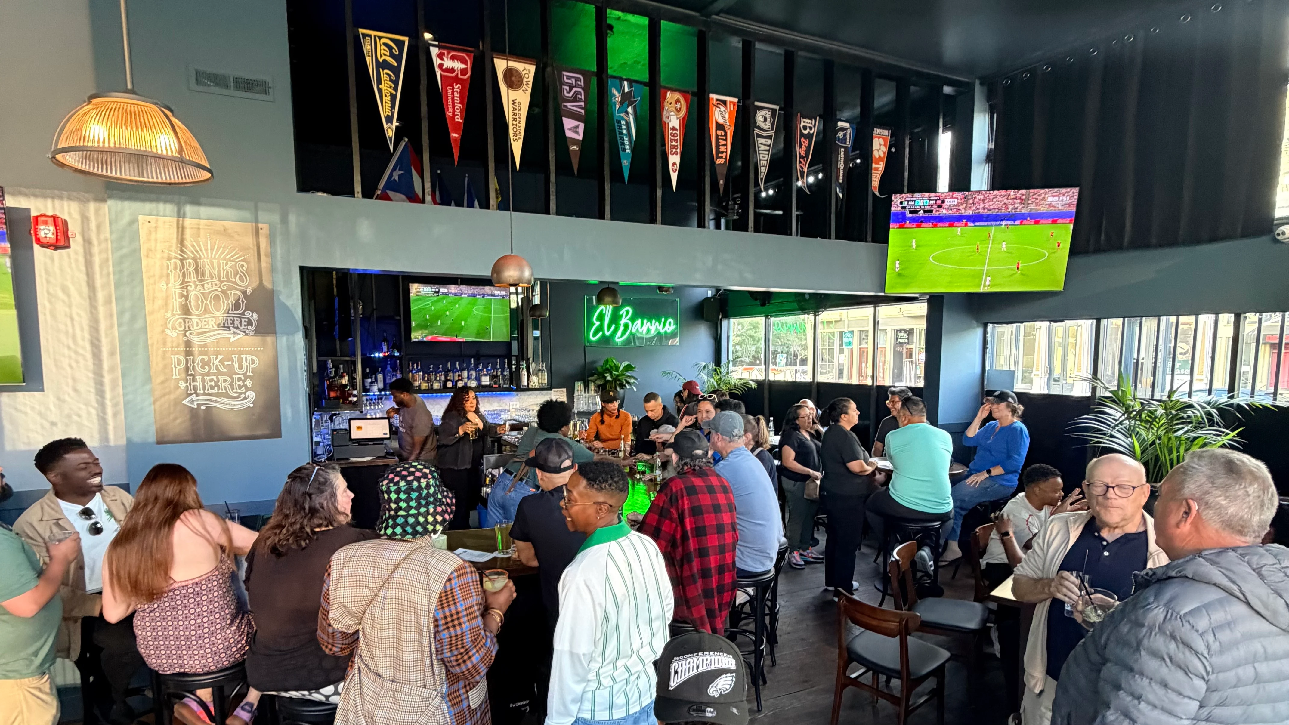 Vibrant bar scene with patrons enjoying drinks and sports on TV