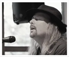 Musician performing live with a microphone and hat