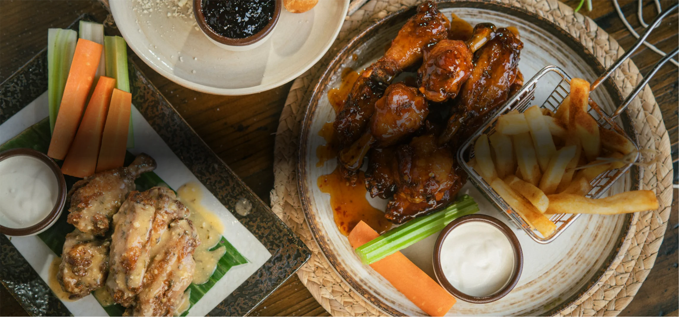 Plate of buffalo chicken wings with dipping sauces and celery sticks