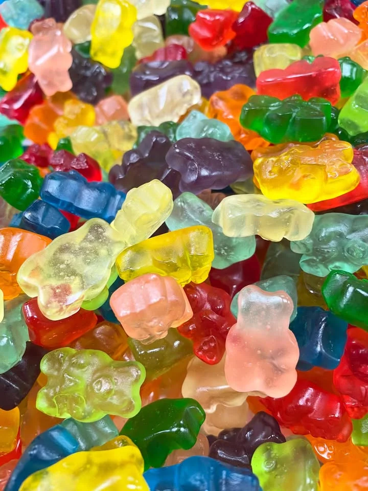 A vibrant assortment of gummy bears in various colors, piled together in a close-up shot.