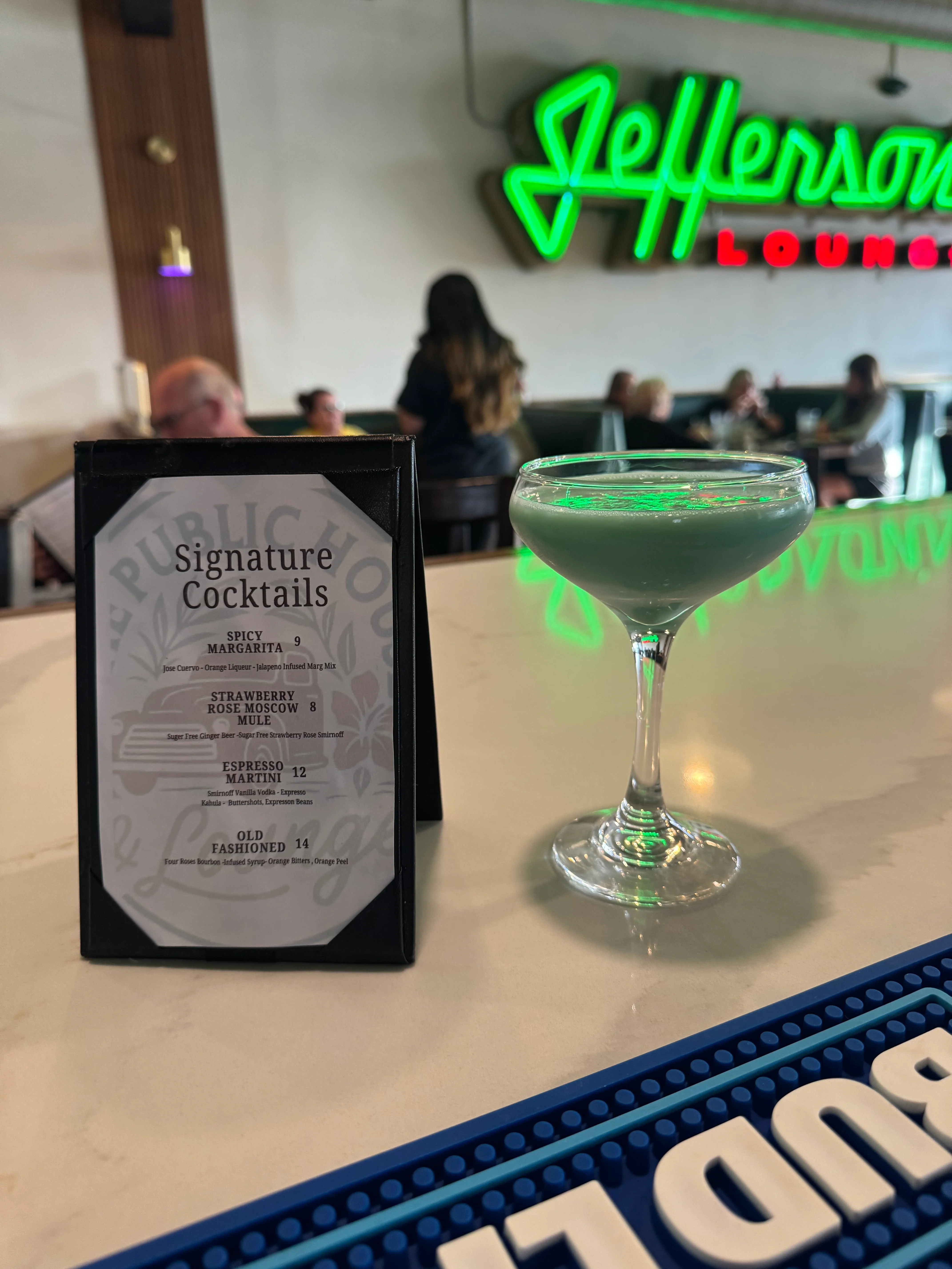 Signature cocktails menu with a green cocktail at Jefferson's Lounge.