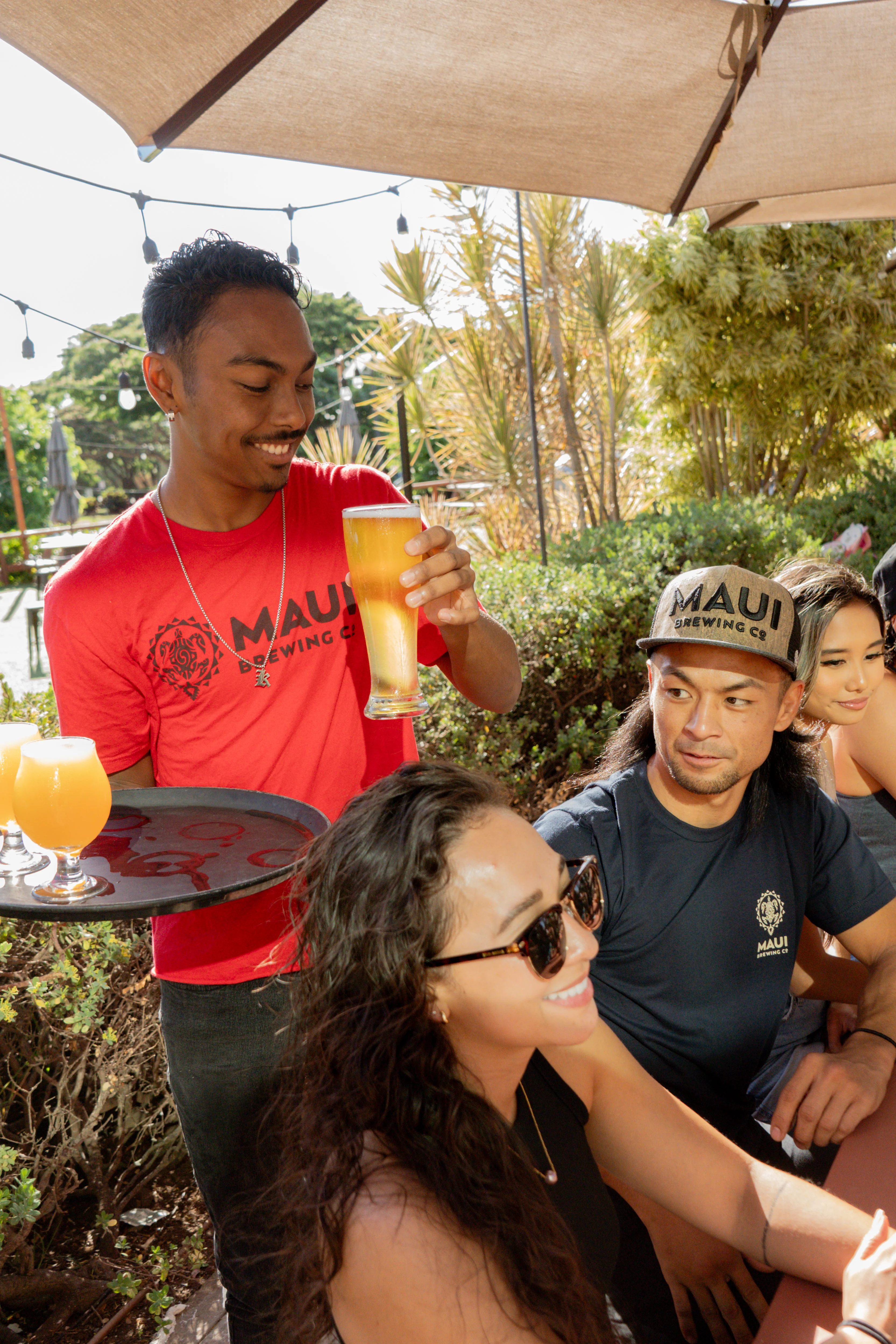 Server presenting craft beer at a vibrant outdoor restaurant