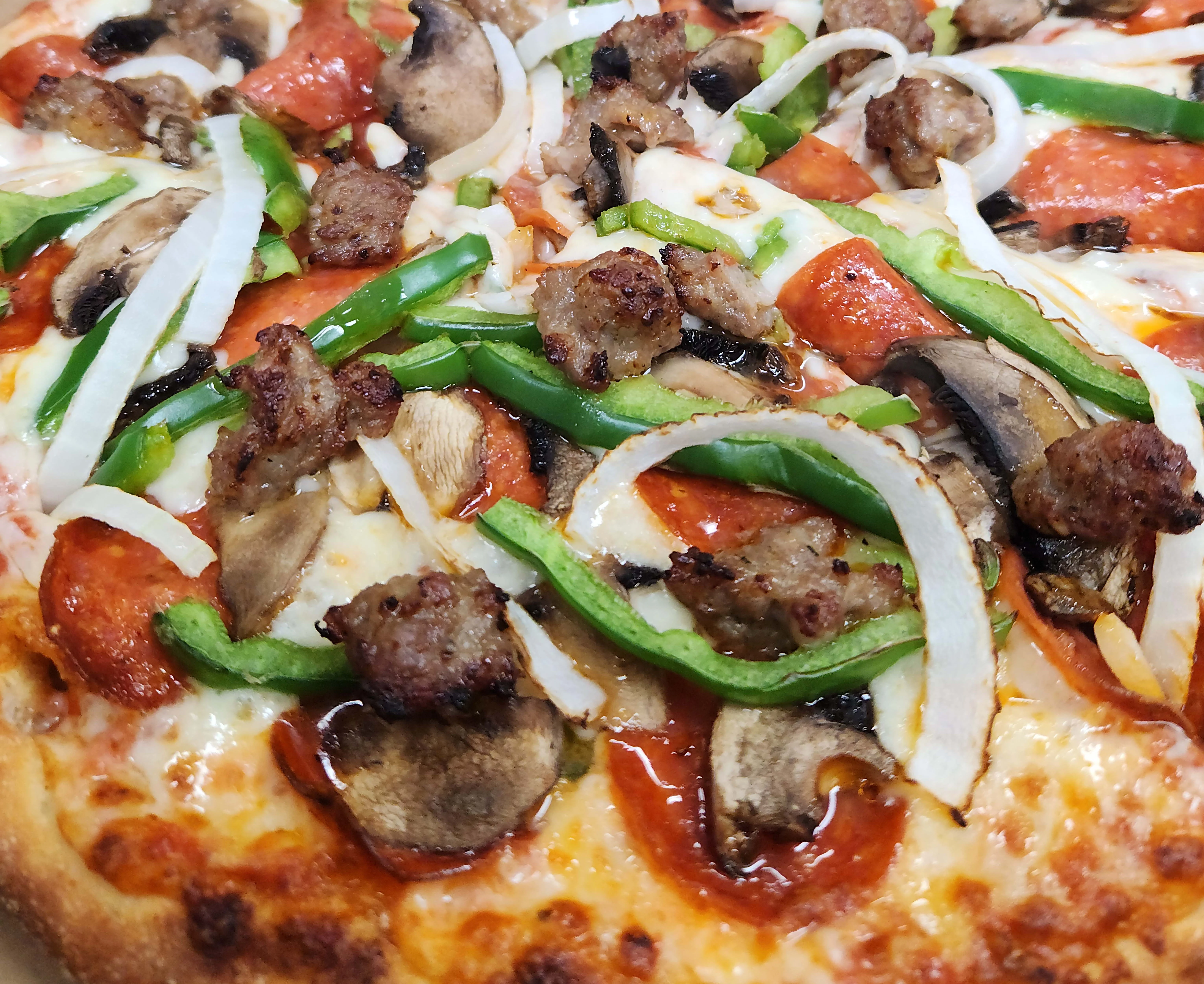 Delicious pepperoni and sausage pizza with green peppers and onions