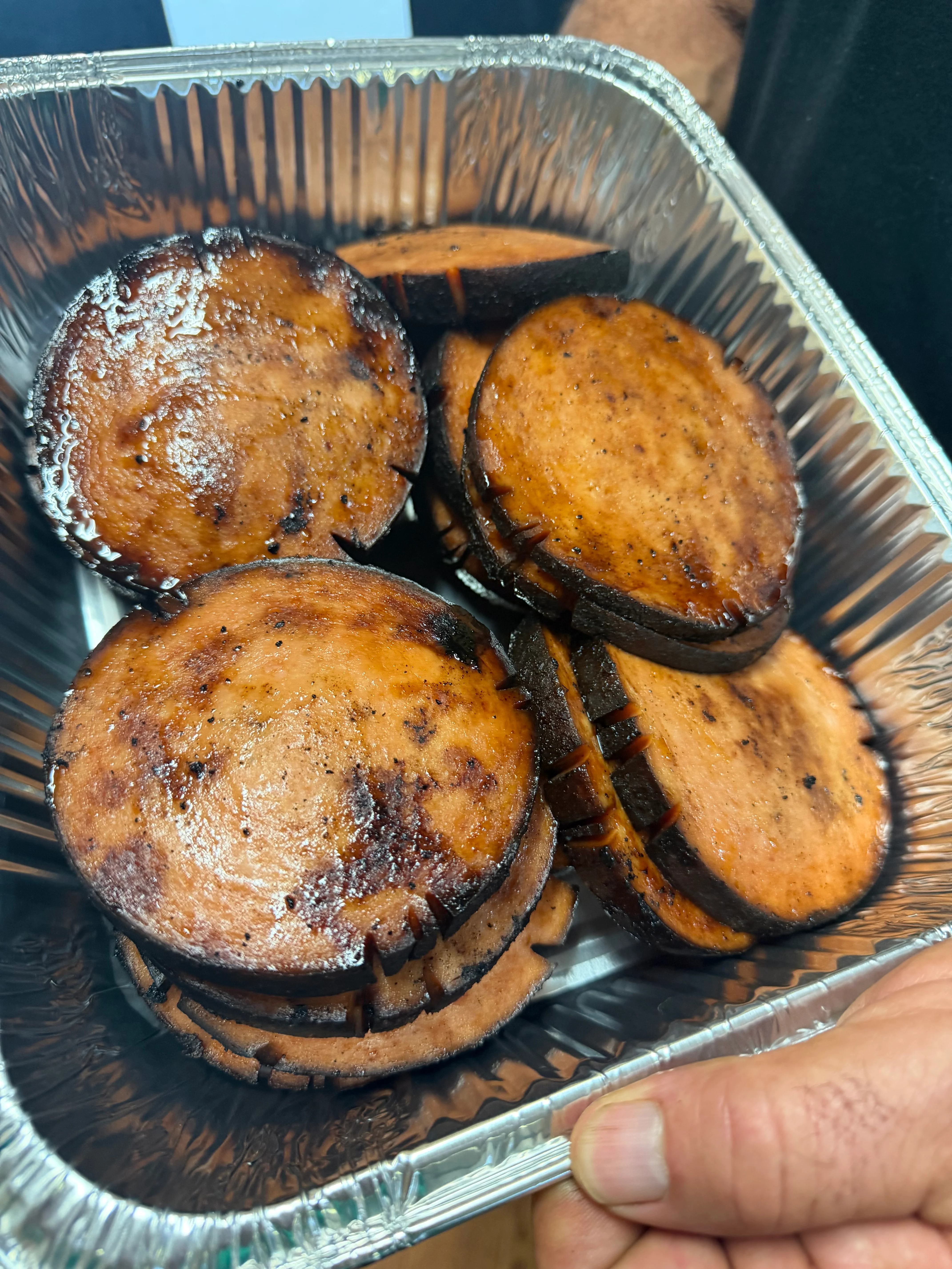 Grilled slices of smoked sausage in a foil tray