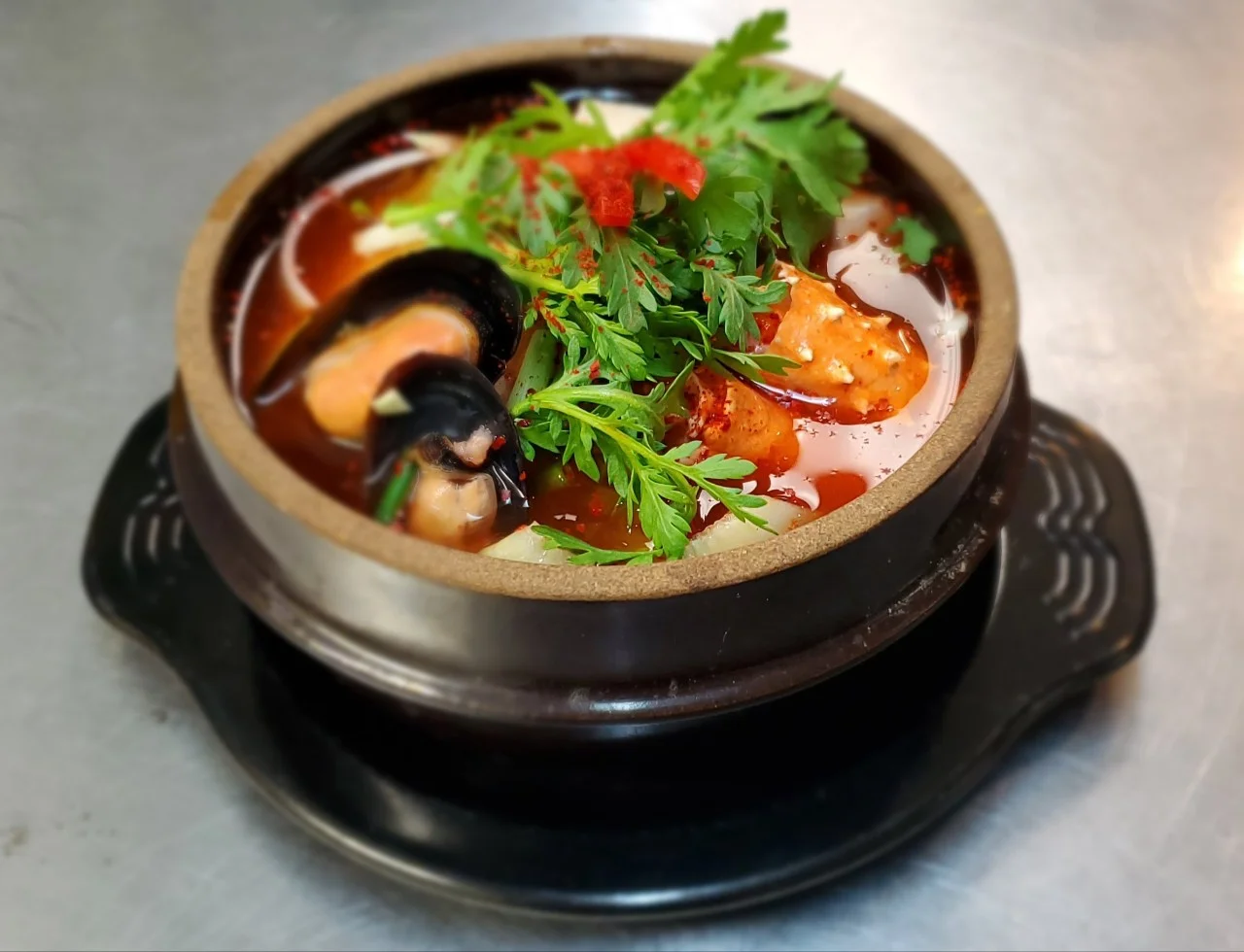 Spicy Thai tom yum soup with seafood in a clay pot