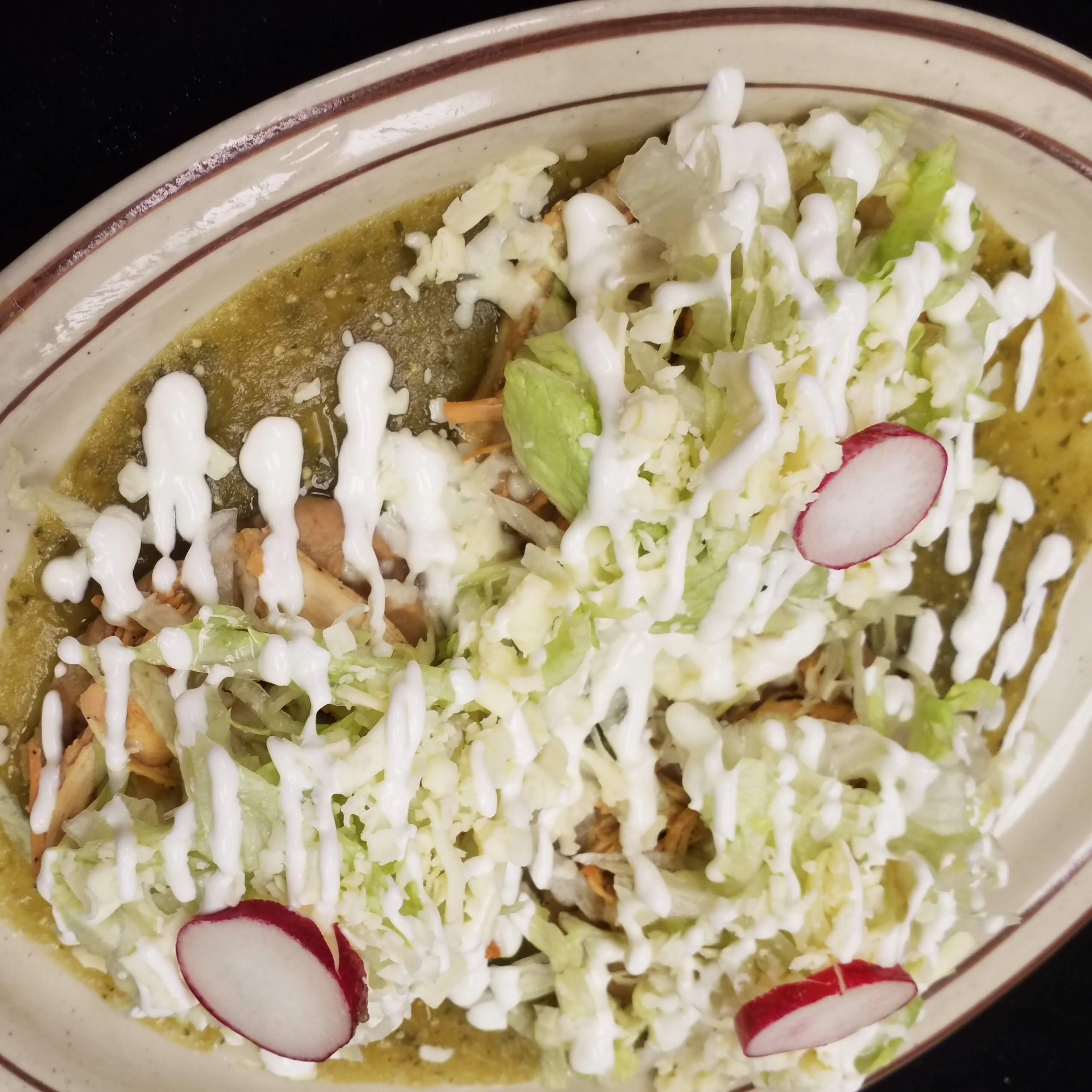 The best Sopes in Radford. A plate of three sopes topped with grilled chicken or steak, refried beans, green salsa, lettuce, cheese, sour cream, and radish slices.