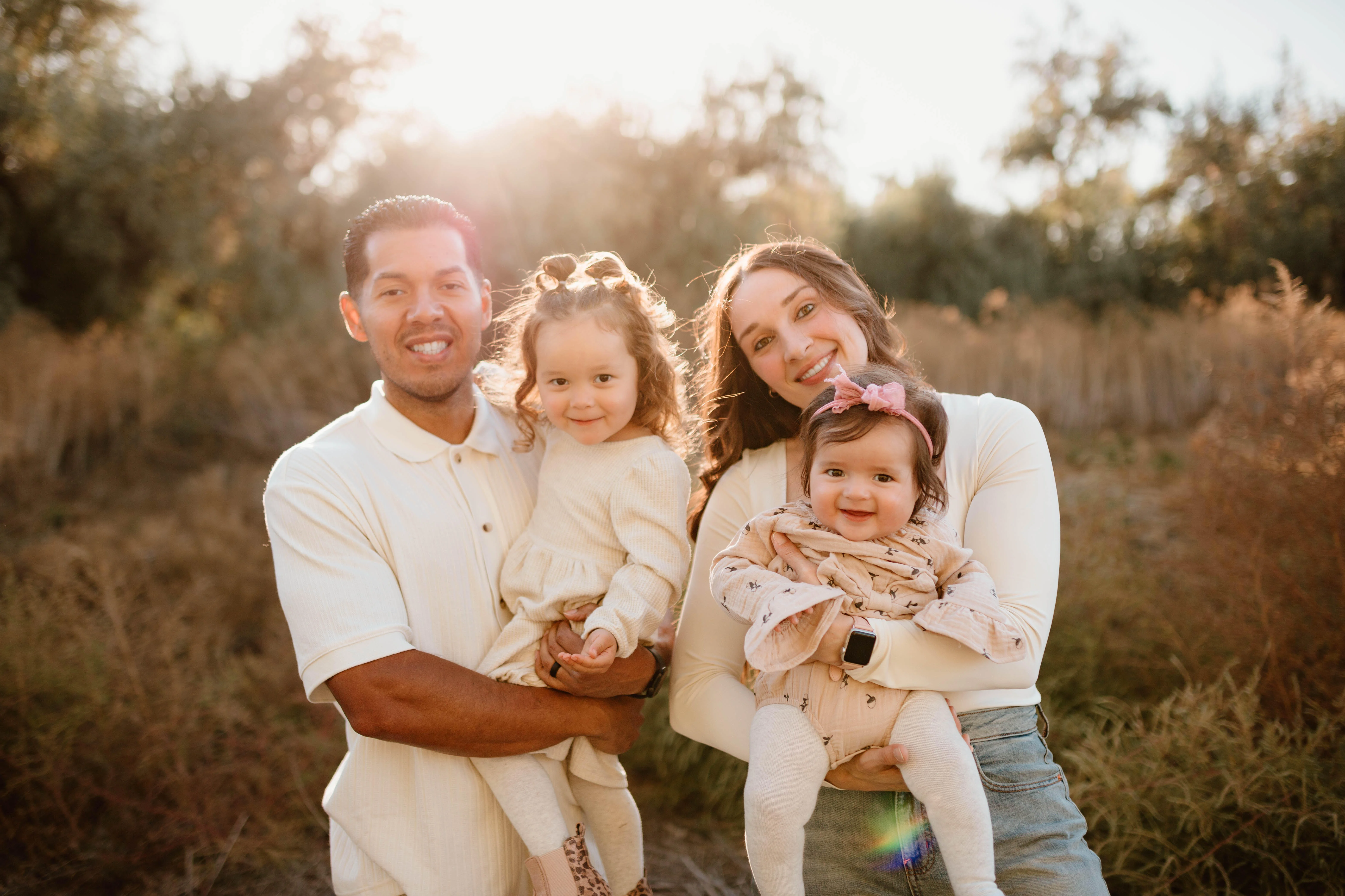Family portrait in a sunlit outdoor setting with two children