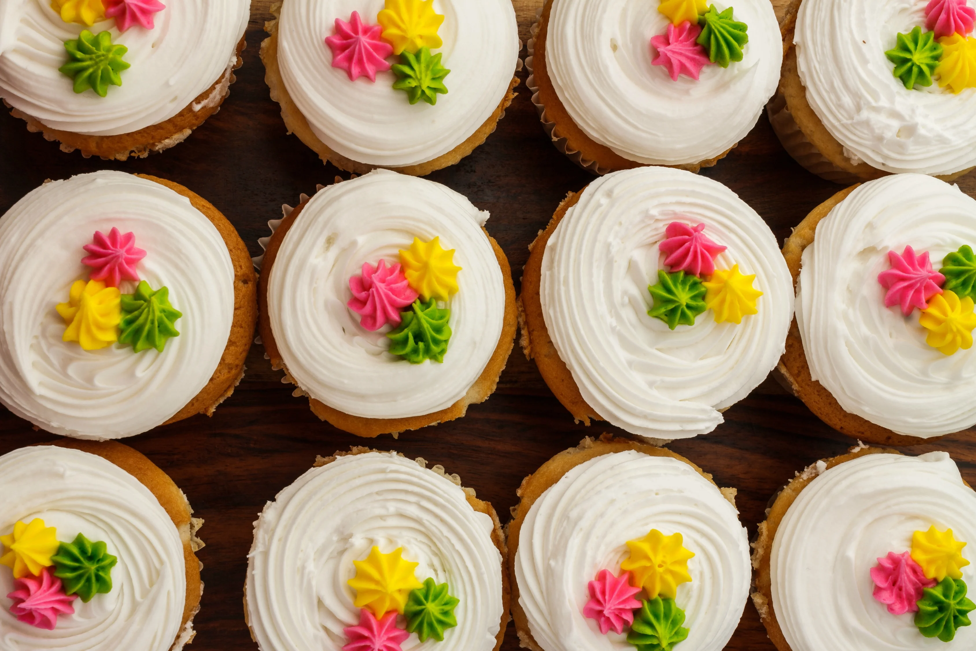 Colorful frosted cupcakes with floral decorations
