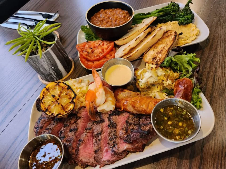 An expansive spread of various snacks and appetizers arranged on a round table. The display includes cured meats, cheeses, crackers, fresh vegetables, and dips.