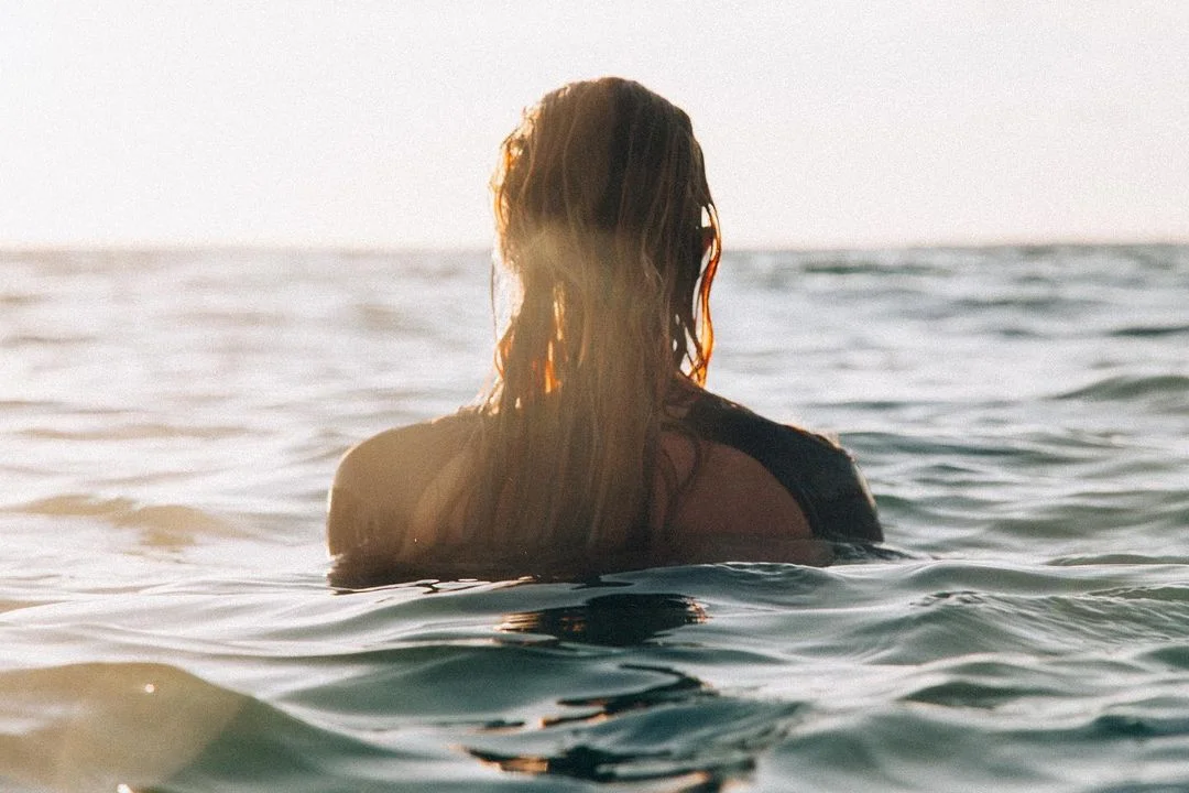 Person swimming in ocean at sunset