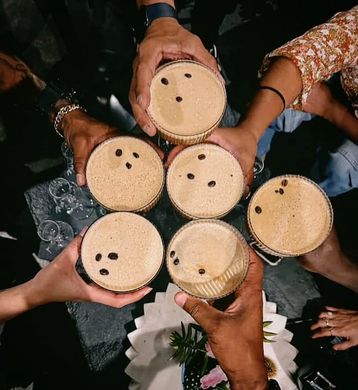 Group of friends toasting with coffee cocktails topped with coffee beans