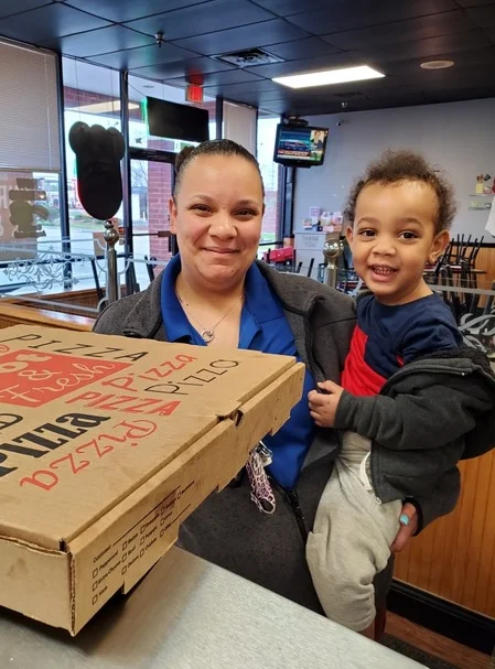 Happy customer holding pizza box in a cozy restaurant
