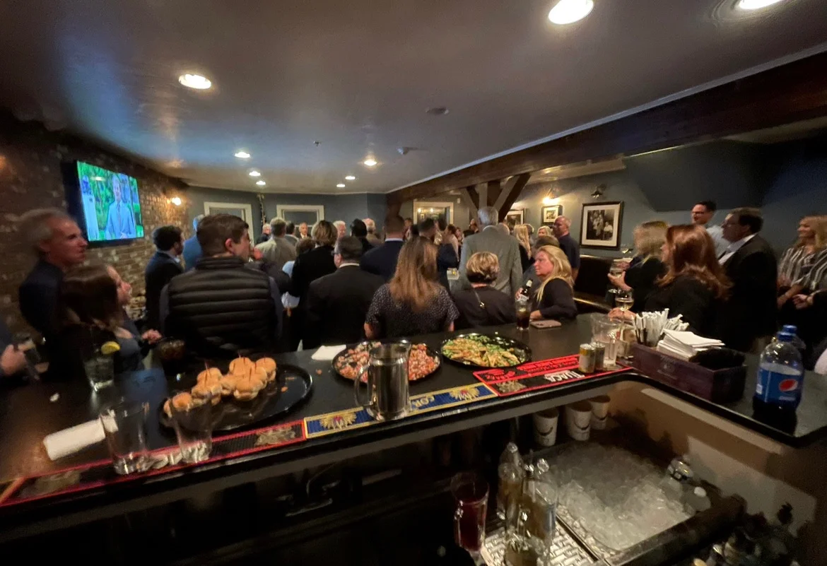 Crowded bar scene with guests enjoying drinks and appetizers
