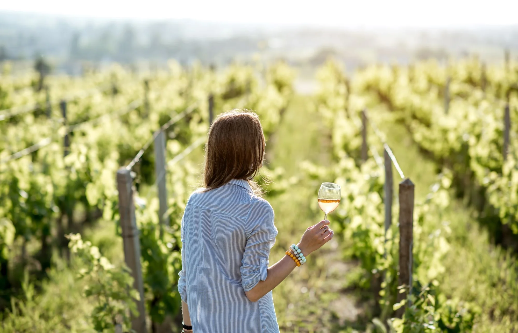 Woman enjoying wine in a sunlit vineyard
