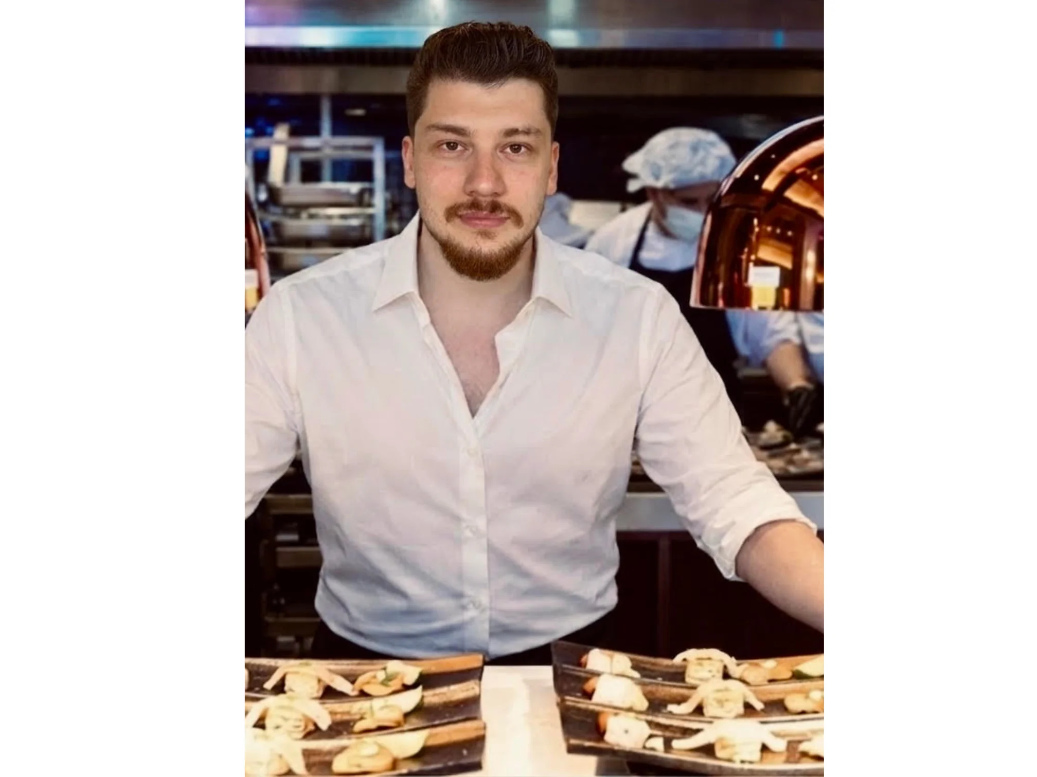 A smiling chef named Brian in a restaurant kitchen.