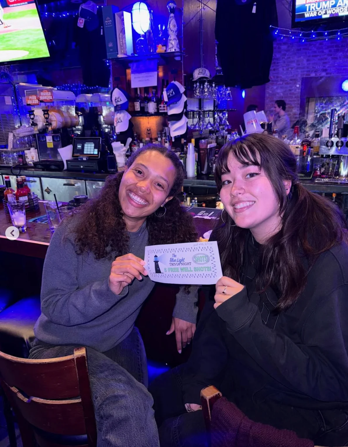 Two friends enjoying trivia night at a lively bar