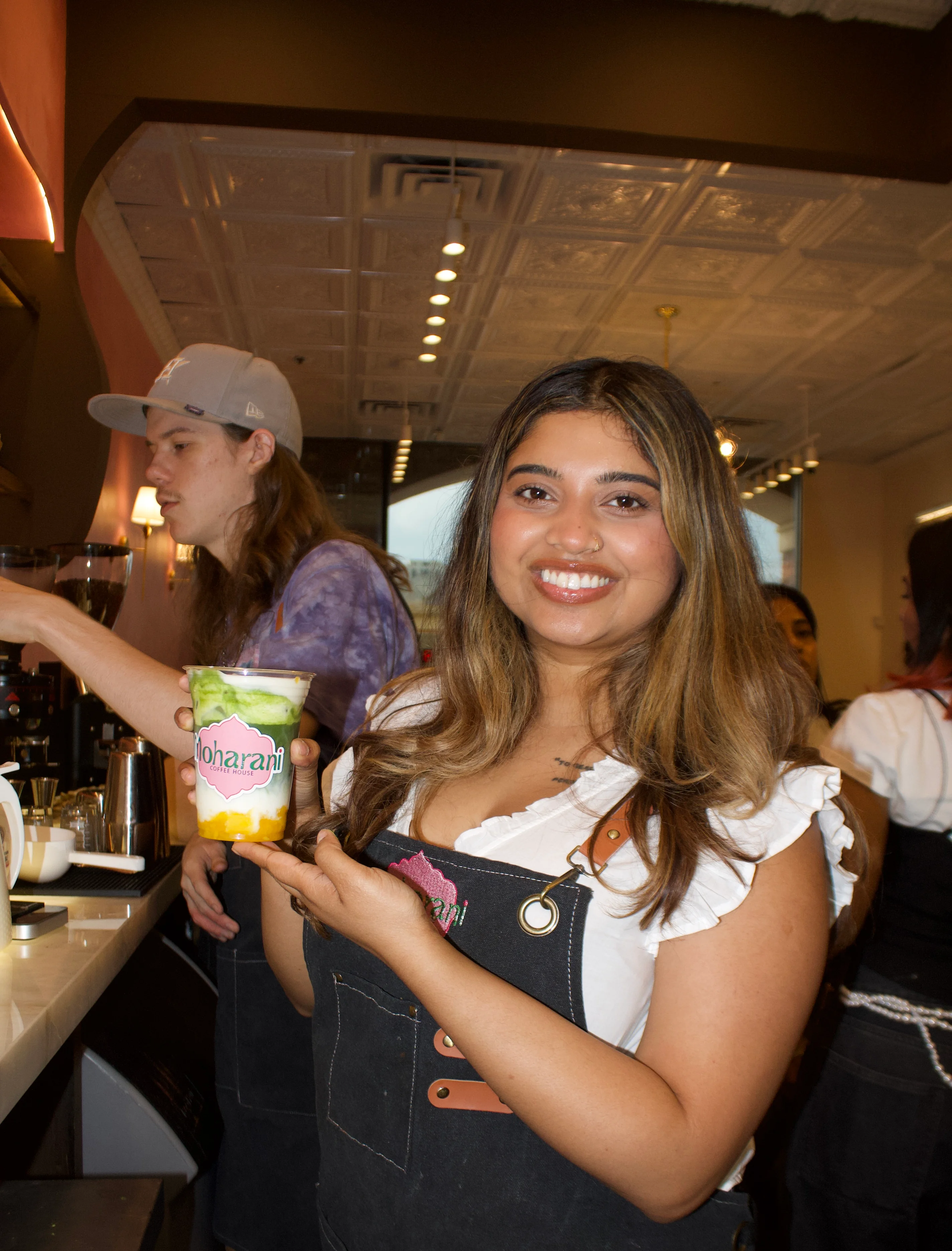 Barista holding a colorful drink at a coffee shop.