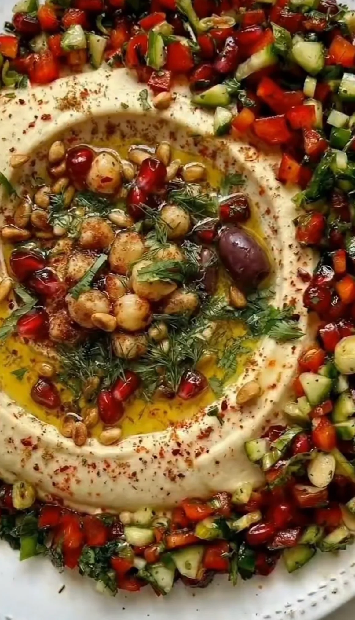 Mediterranean hummus topped with fresh vegetables and herbs