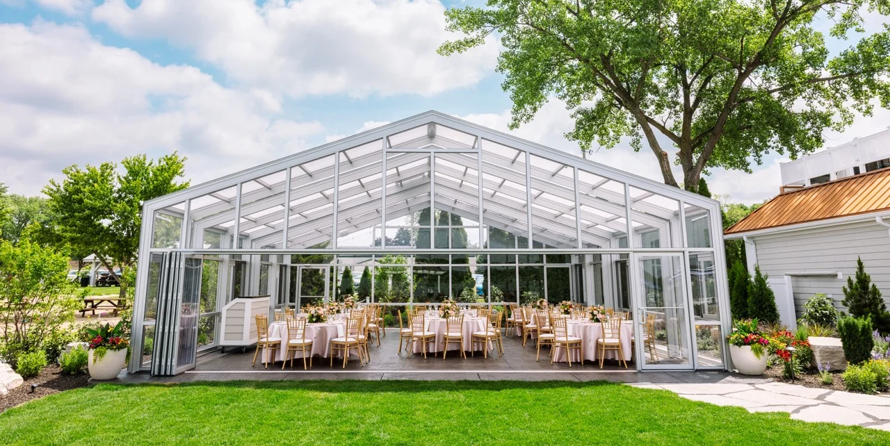 Elegant glass-enclosed dining venue with tables and greenery