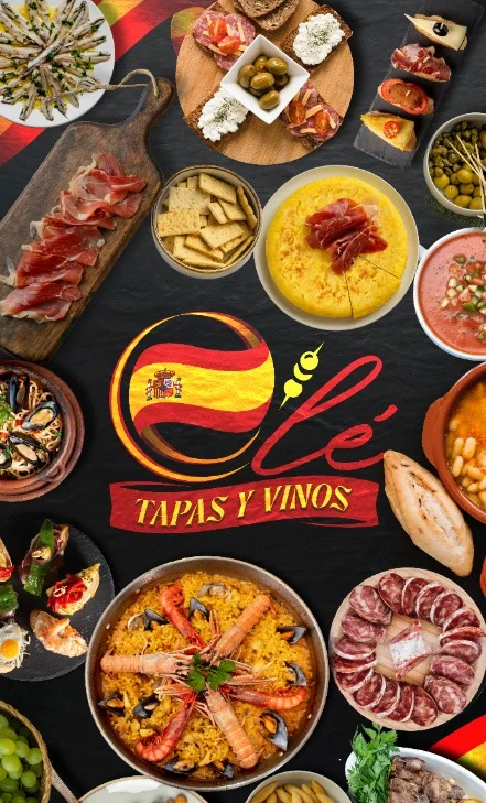 A vibrant assortment of tapas including olives, cured meats, cheese, and vegetables, accompanied by two glasses of beer. The ingredients are spread out on a rustic wooden table.