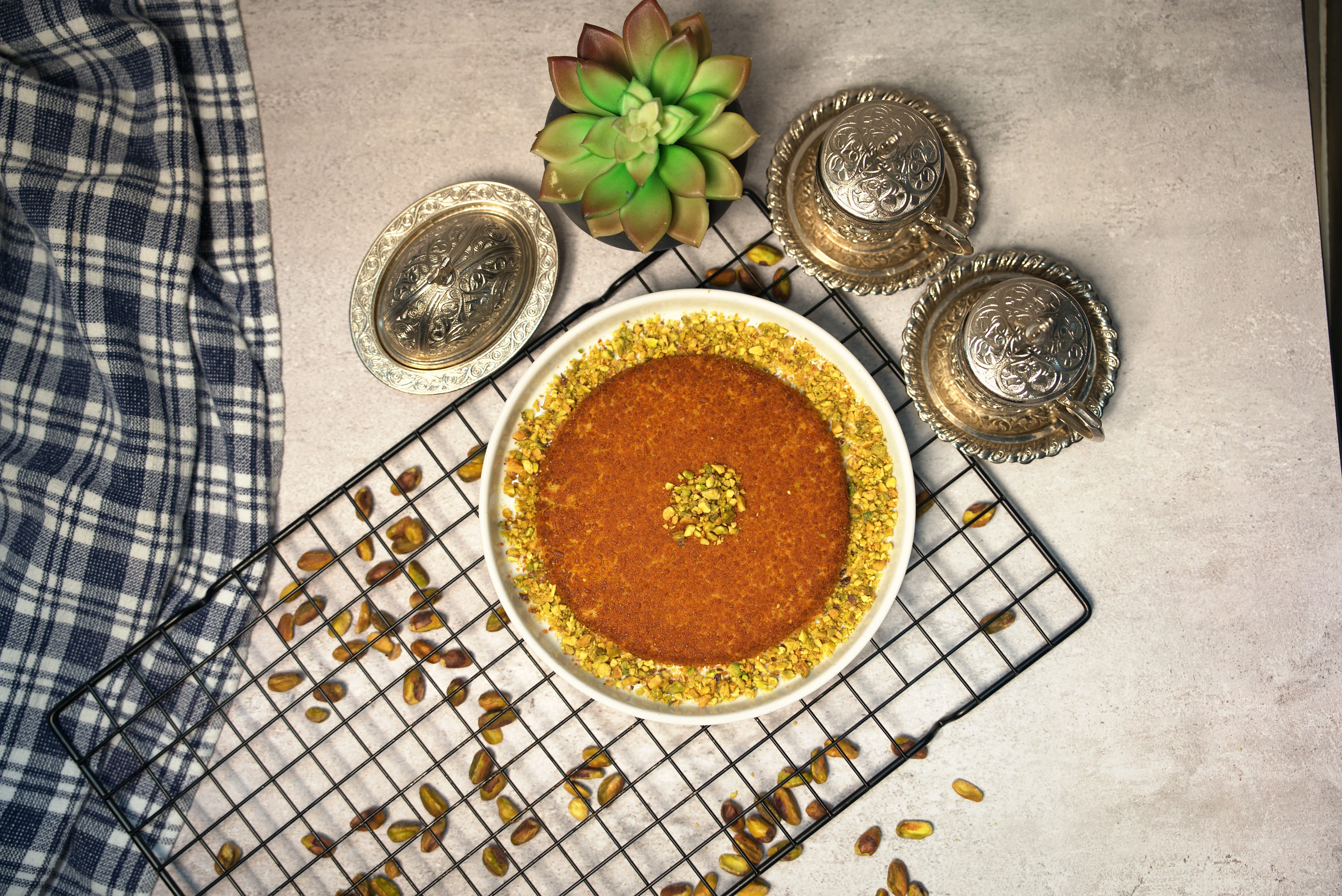 An enticing arrangement of multiple traditional desserts, each with unique toppings, served on white and gold plates against a textured brown background.