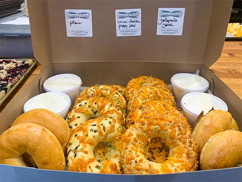 Assorted bagels with cream cheese in a takeout box