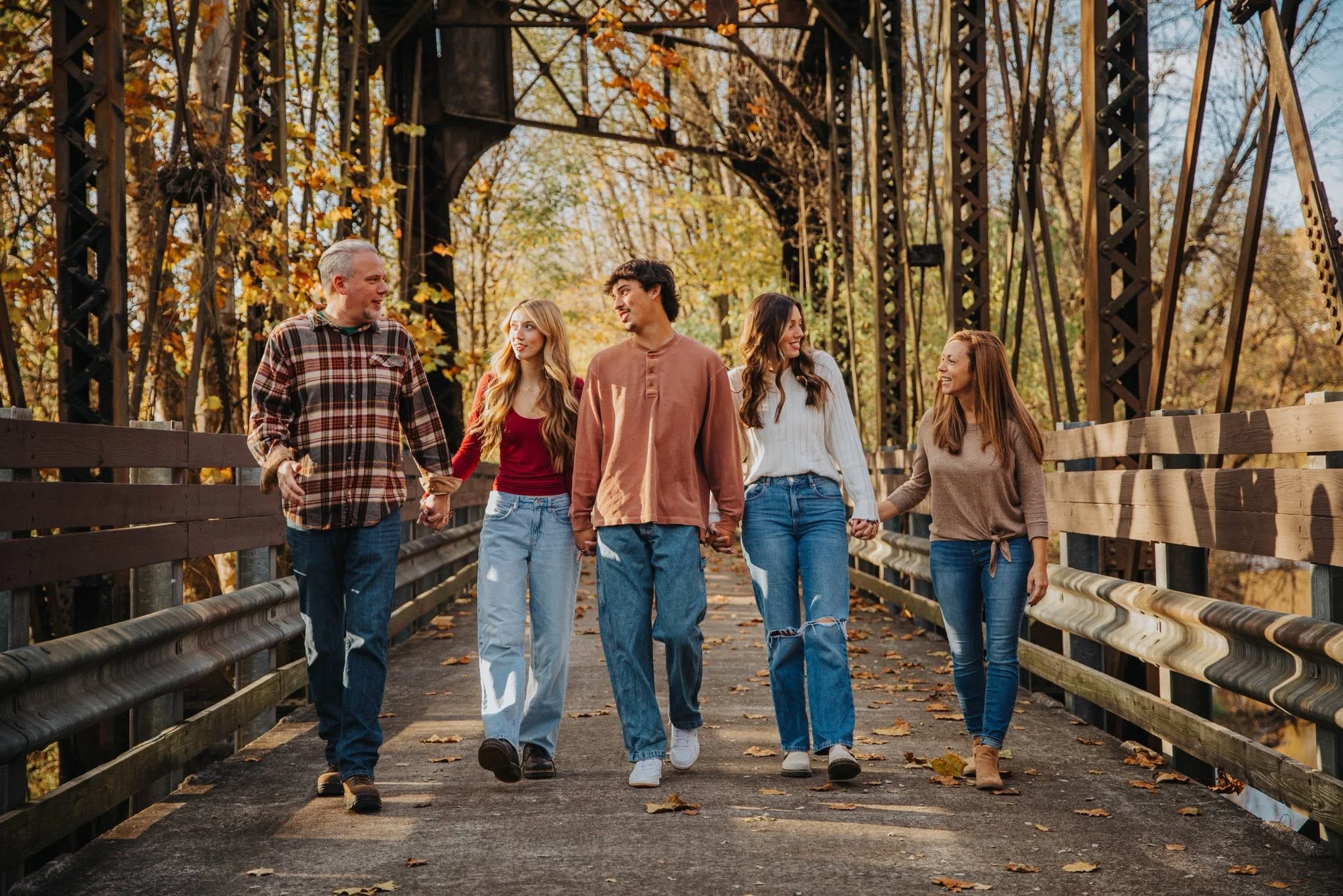 Three friends posing on a bridge surrounded by autumn leaves