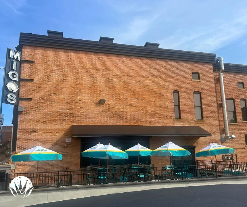 Exterior view of Migos restaurant with patio seating and umbrellas