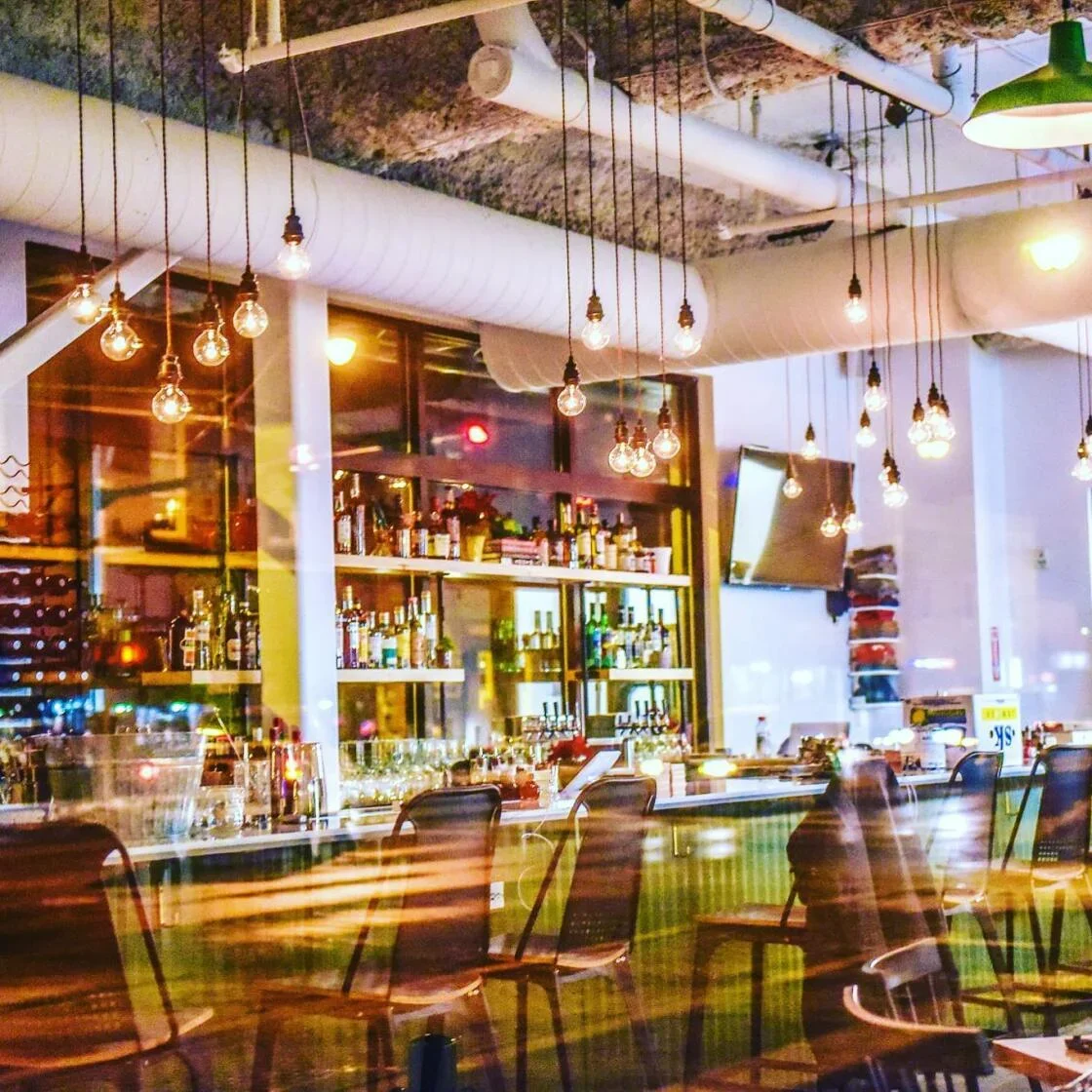 Modern restaurant bar interior with pendant lighting and exposed ceiling ducts