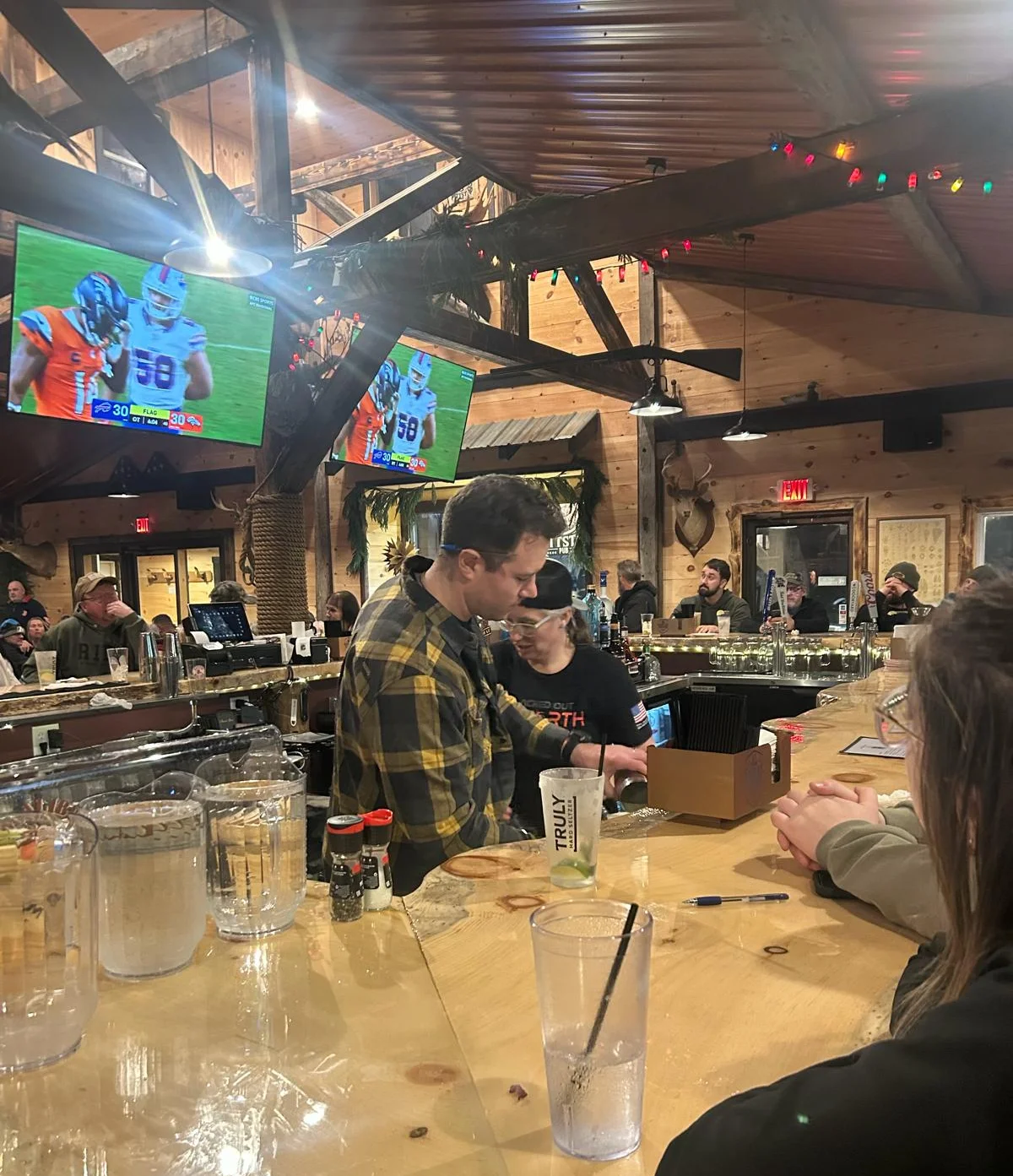 Cozy bar scene with patrons enjoying drinks and sports on TV