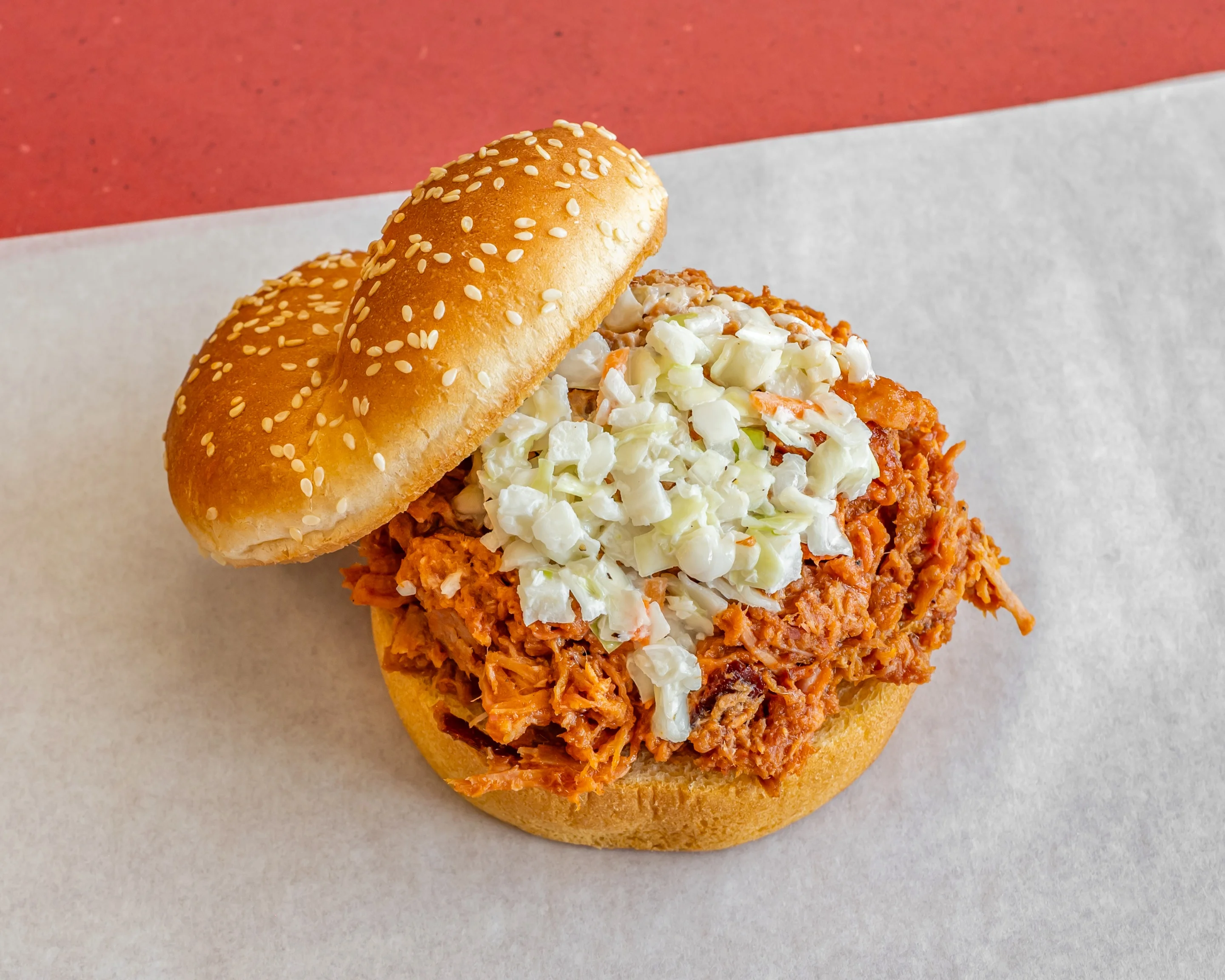 barbeque sandwich with coleslaw and sesame bun on deli wrap pan liner