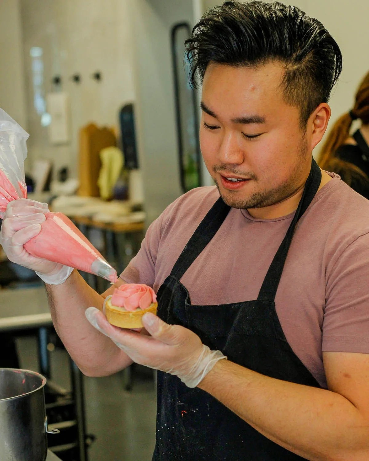 Baker decorating a cupcake with pink frosting