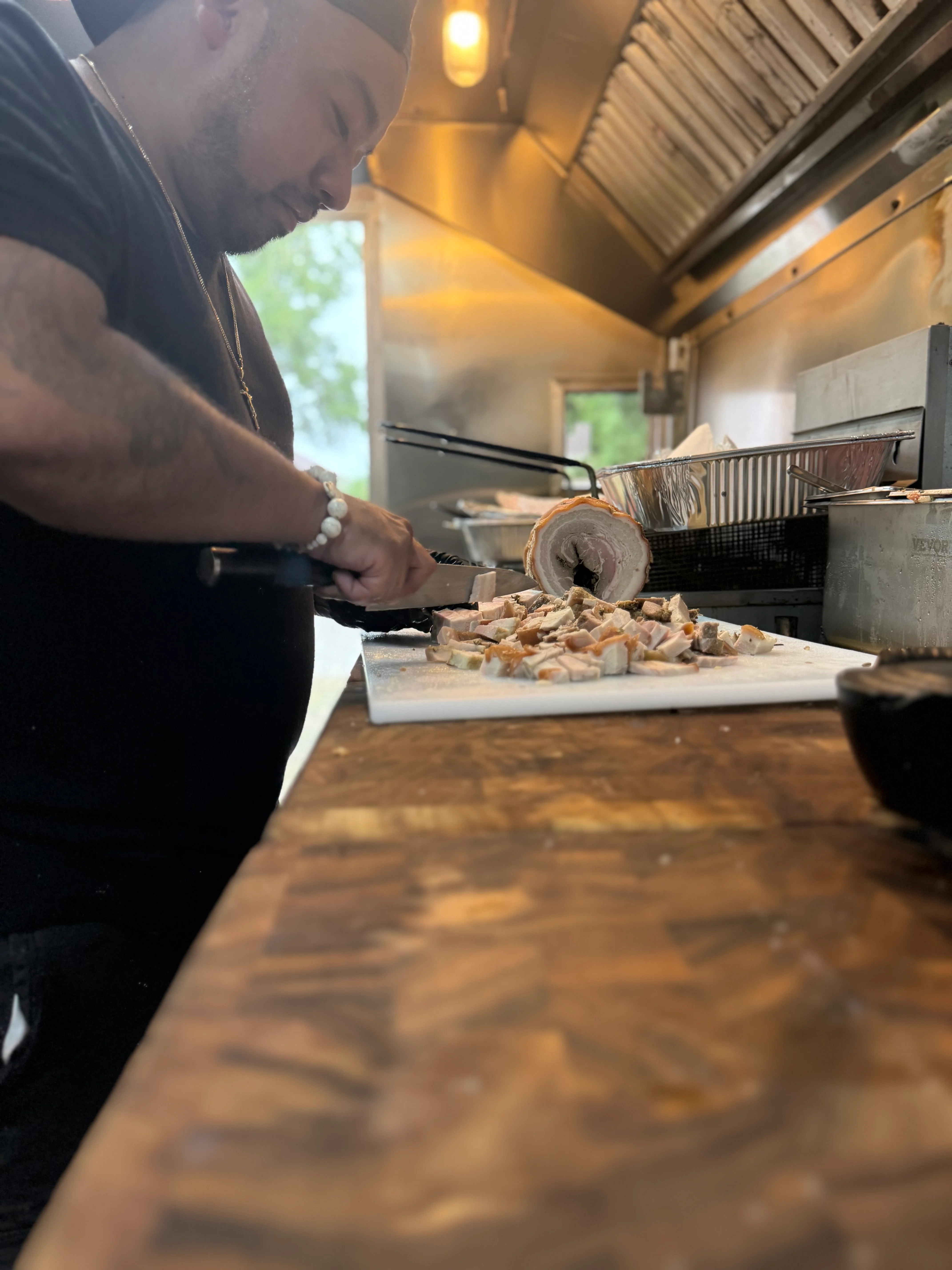 Chef slicing roasted pork in a food truck kitchen