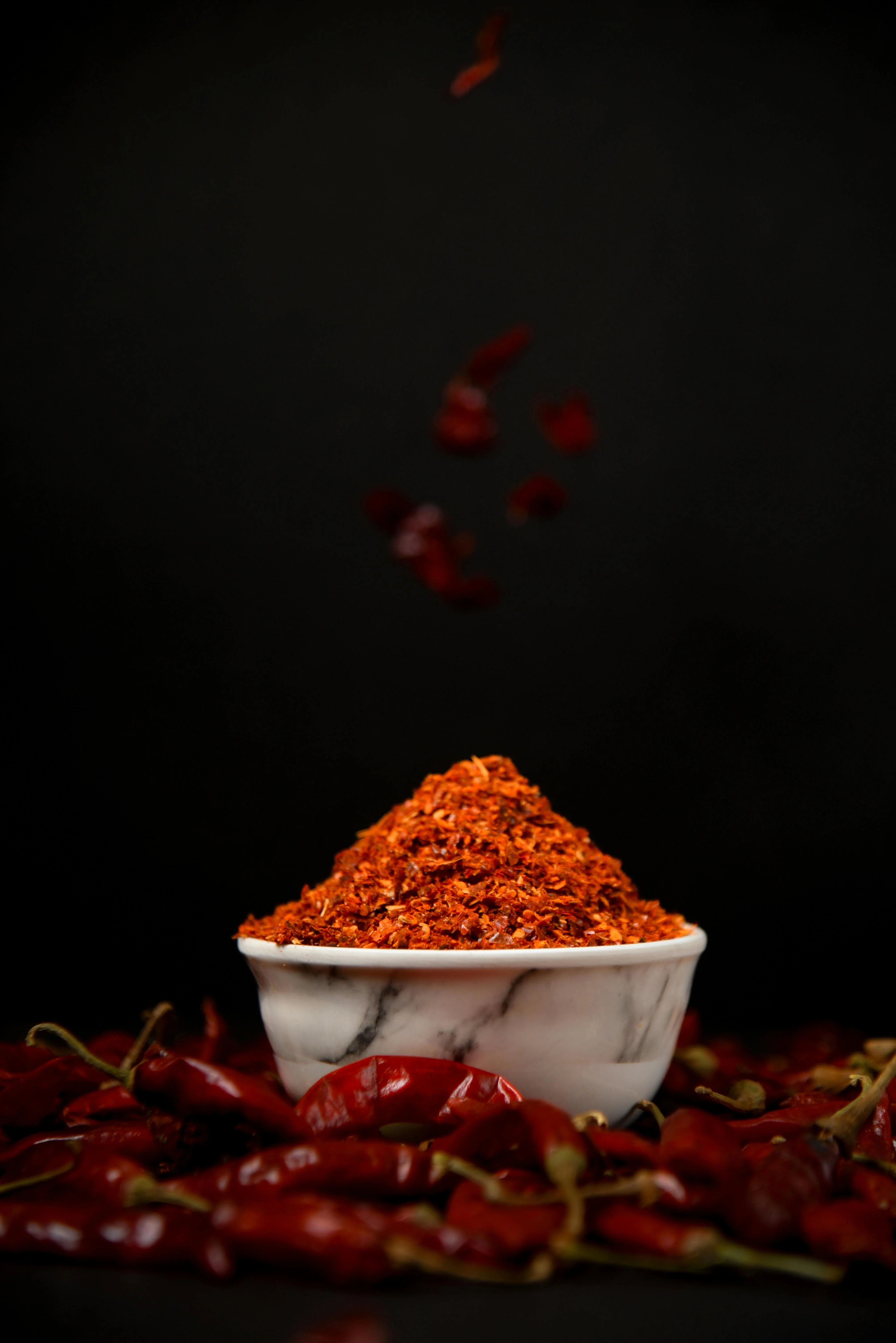 Vibrant bowl of Indian red chili powder against a dark background