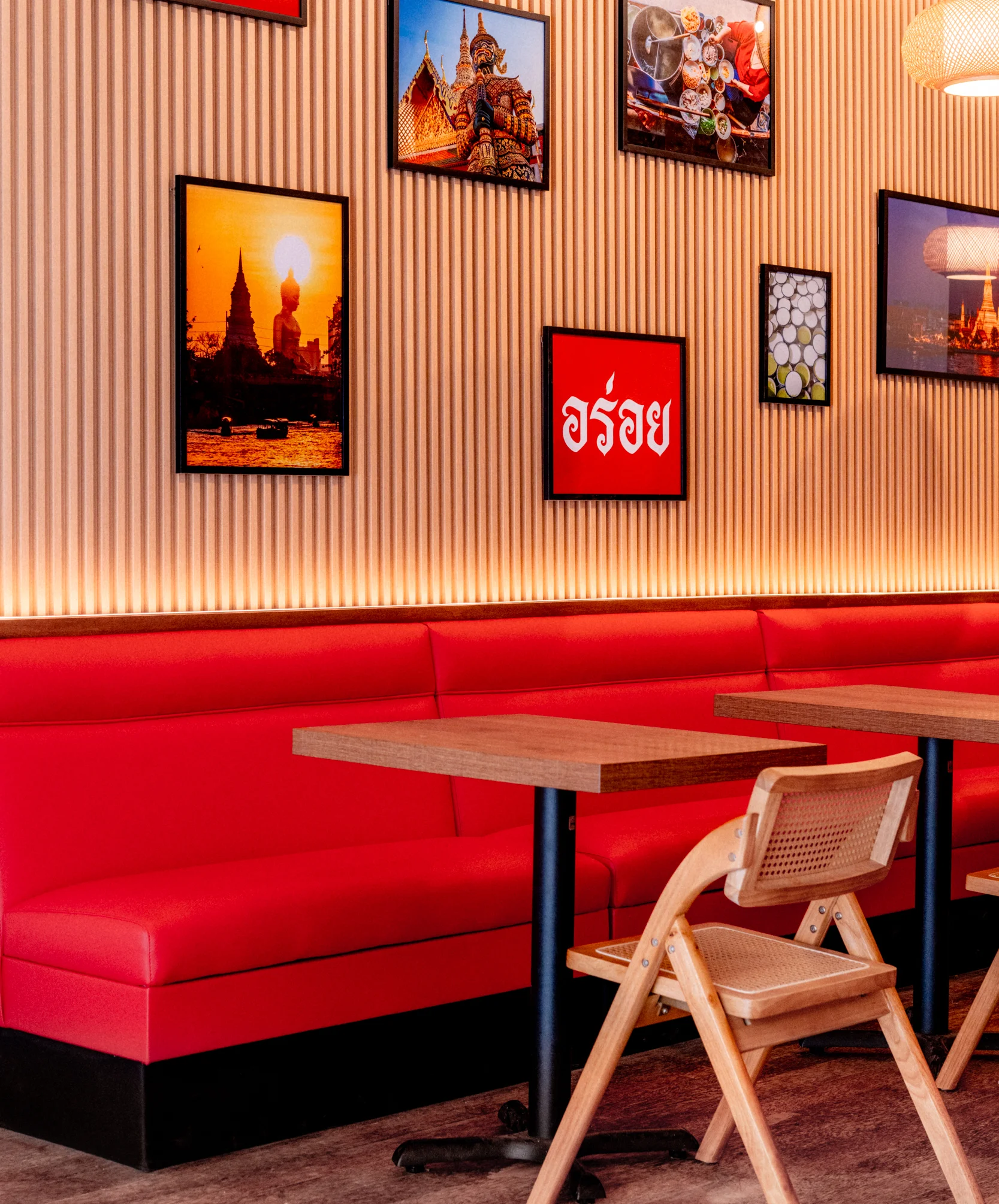 Modern restaurant interior with red seating and cultural artwork